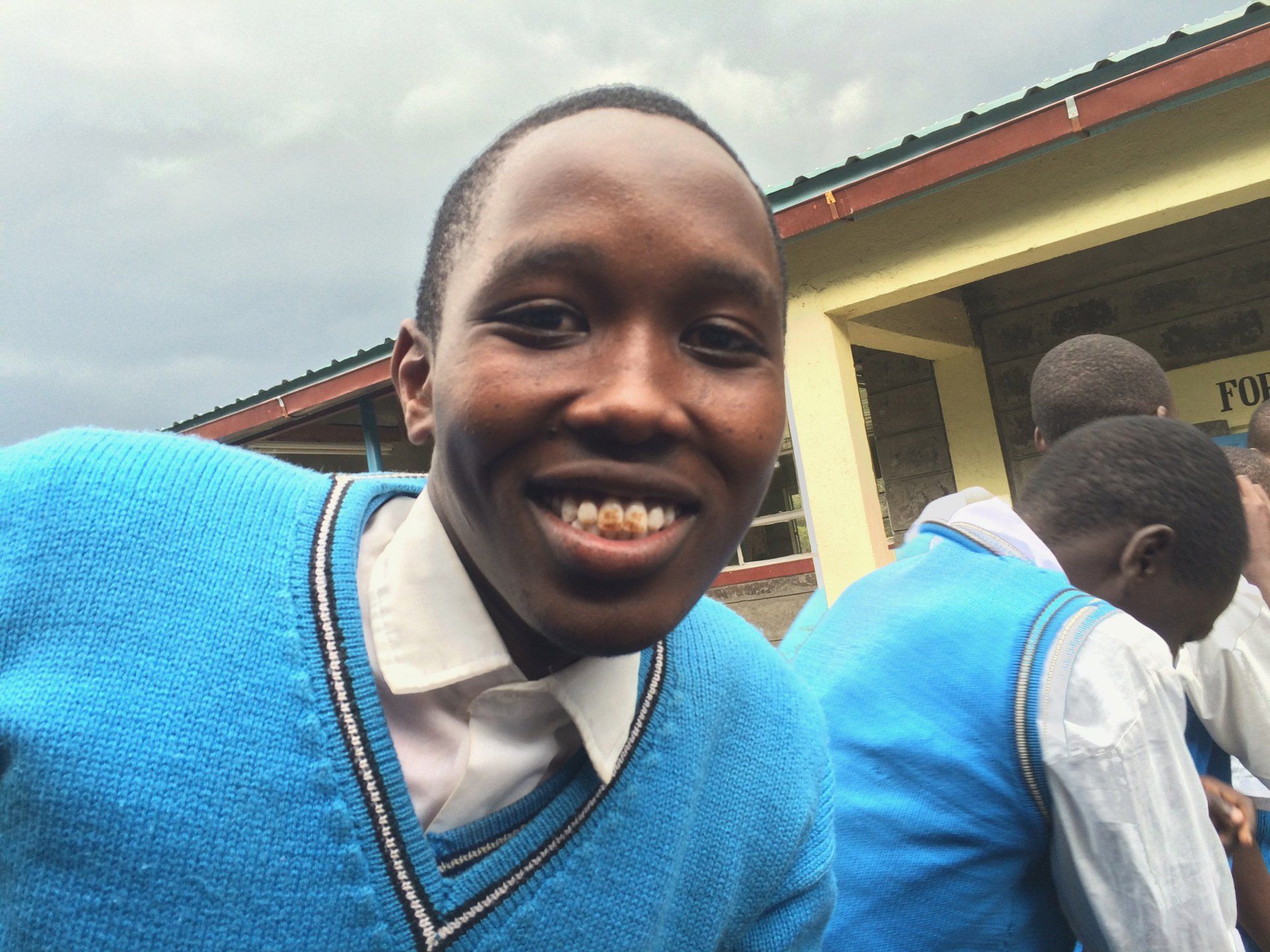 A boy in a blue sweater is smiling for the camera