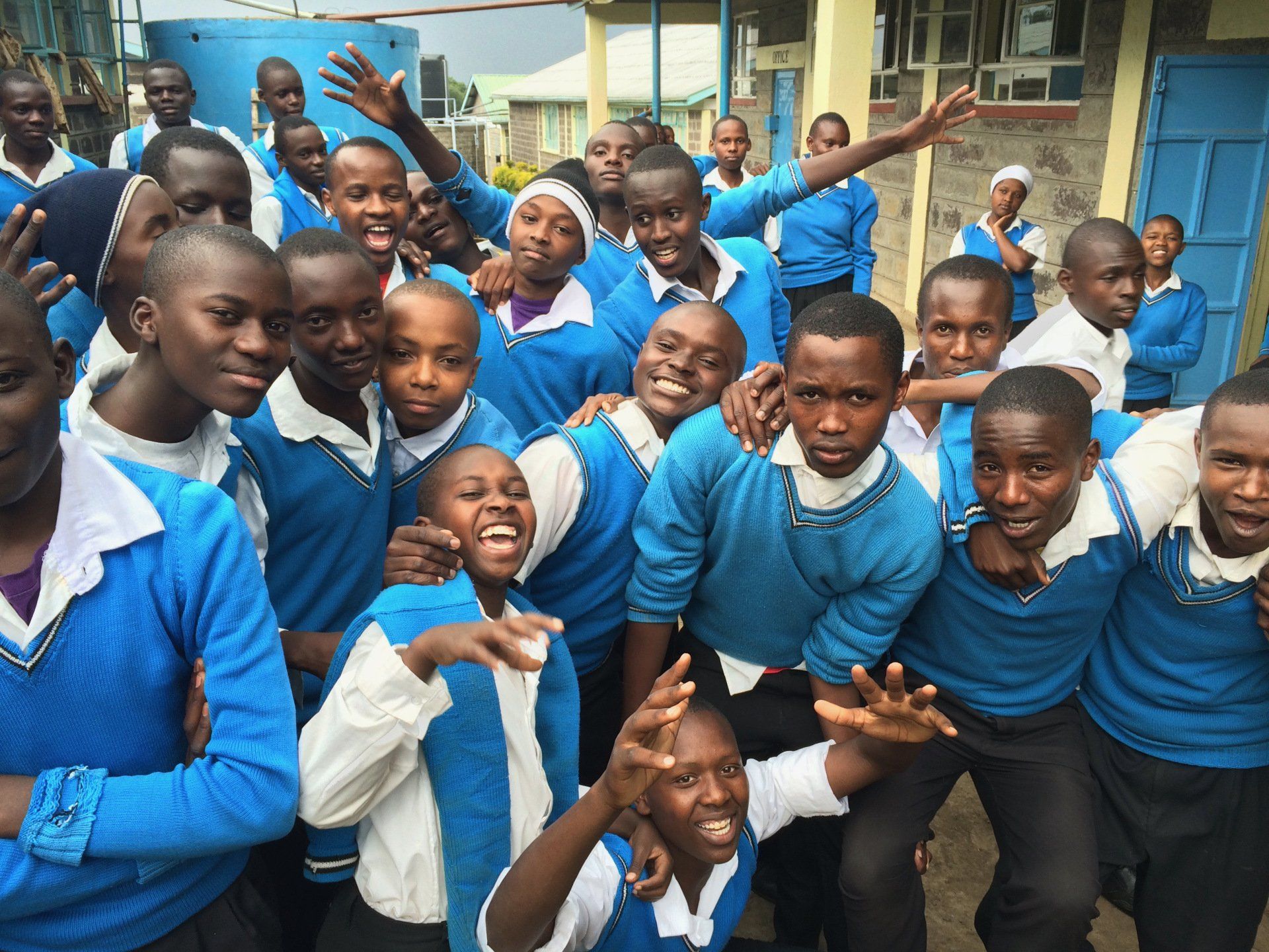 A group of children in blue sweaters are posing for a picture