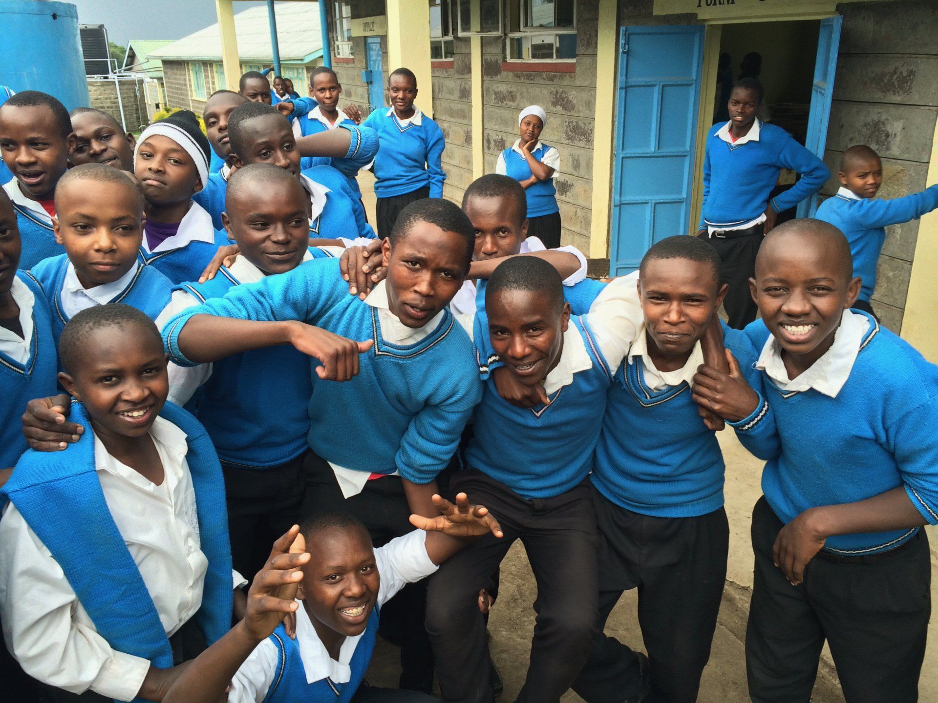 A group of children in blue sweaters are posing for a picture