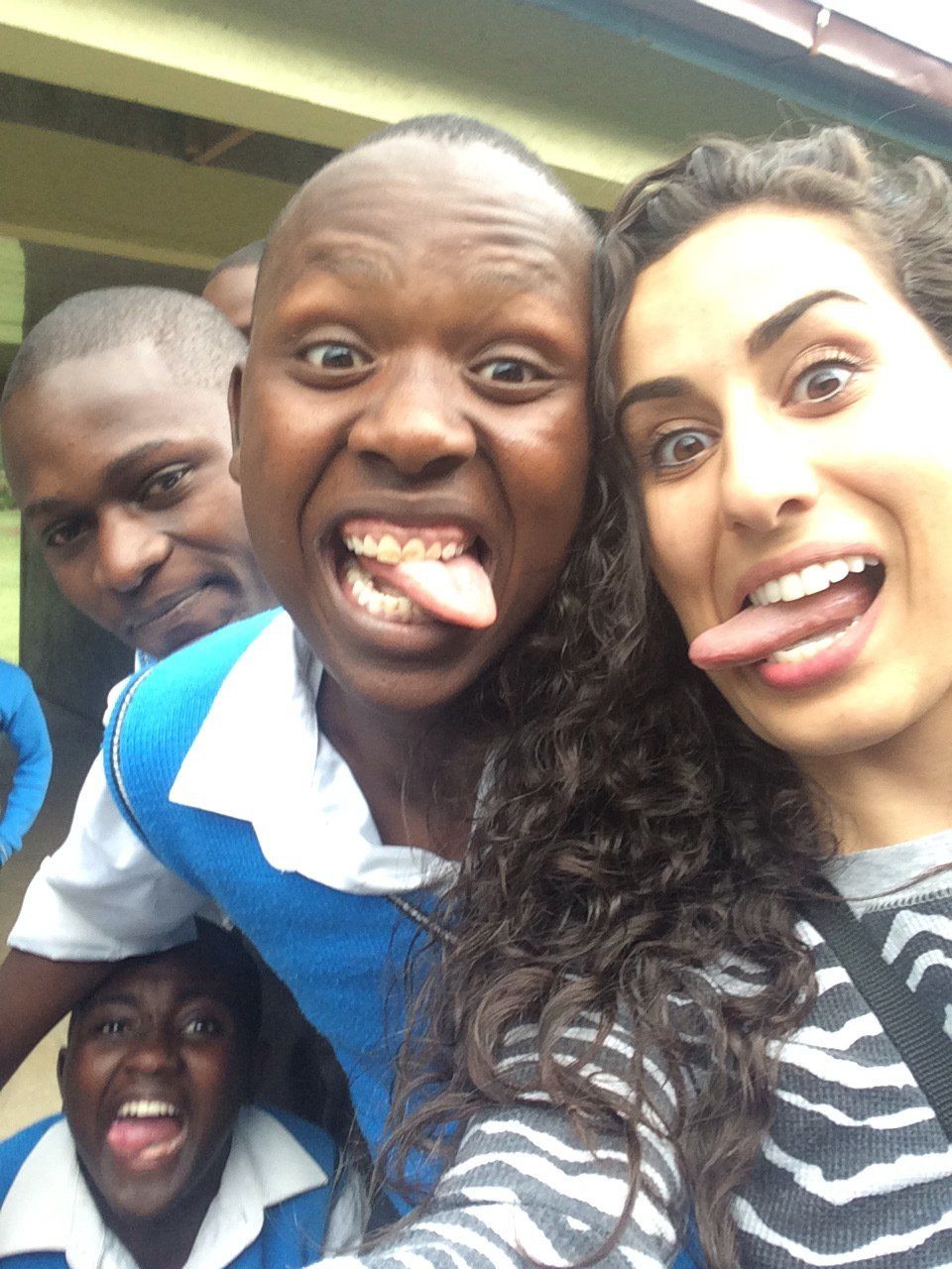 A group of people are posing for a picture with one sticking out her tongue