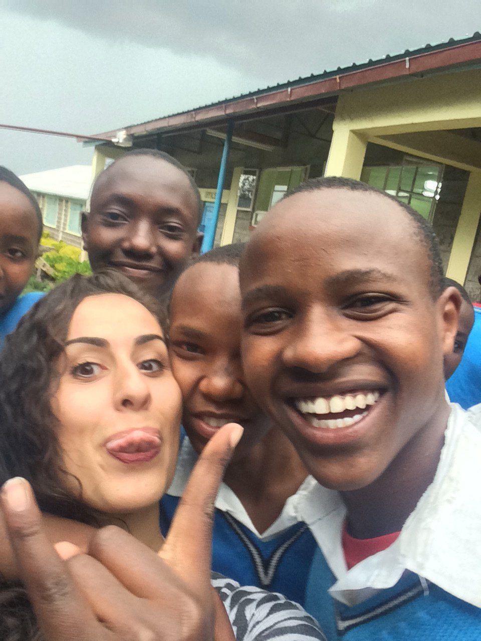 A group of people are posing for a picture and one girl is sticking her tongue out