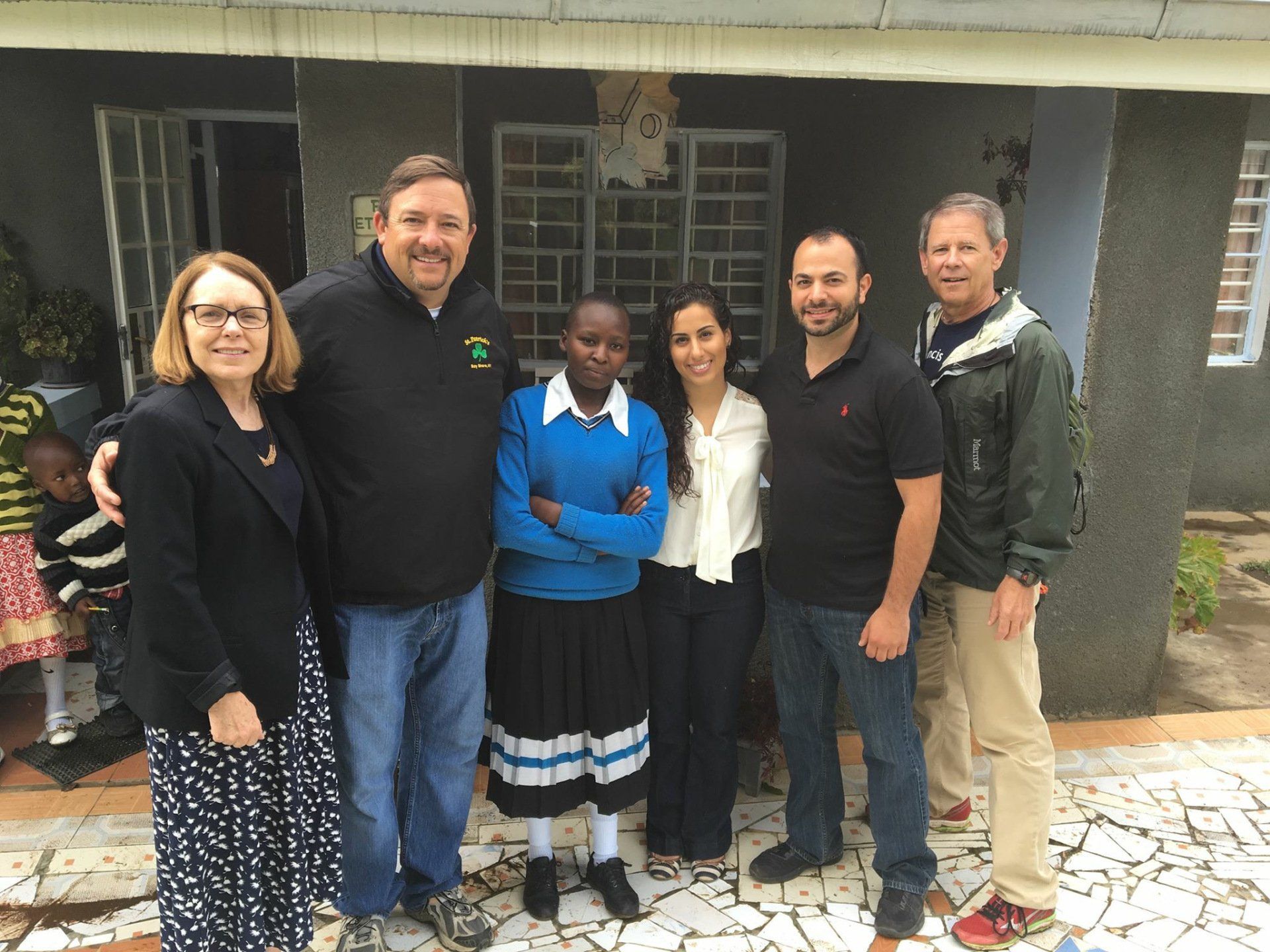 A group of people are posing for a picture in front of a house.