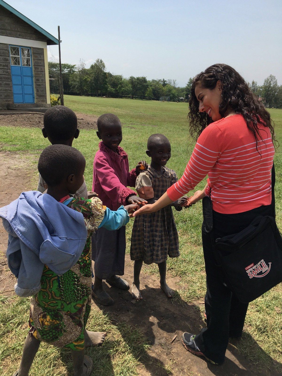 A woman in a red striped shirt is talking to a group of children