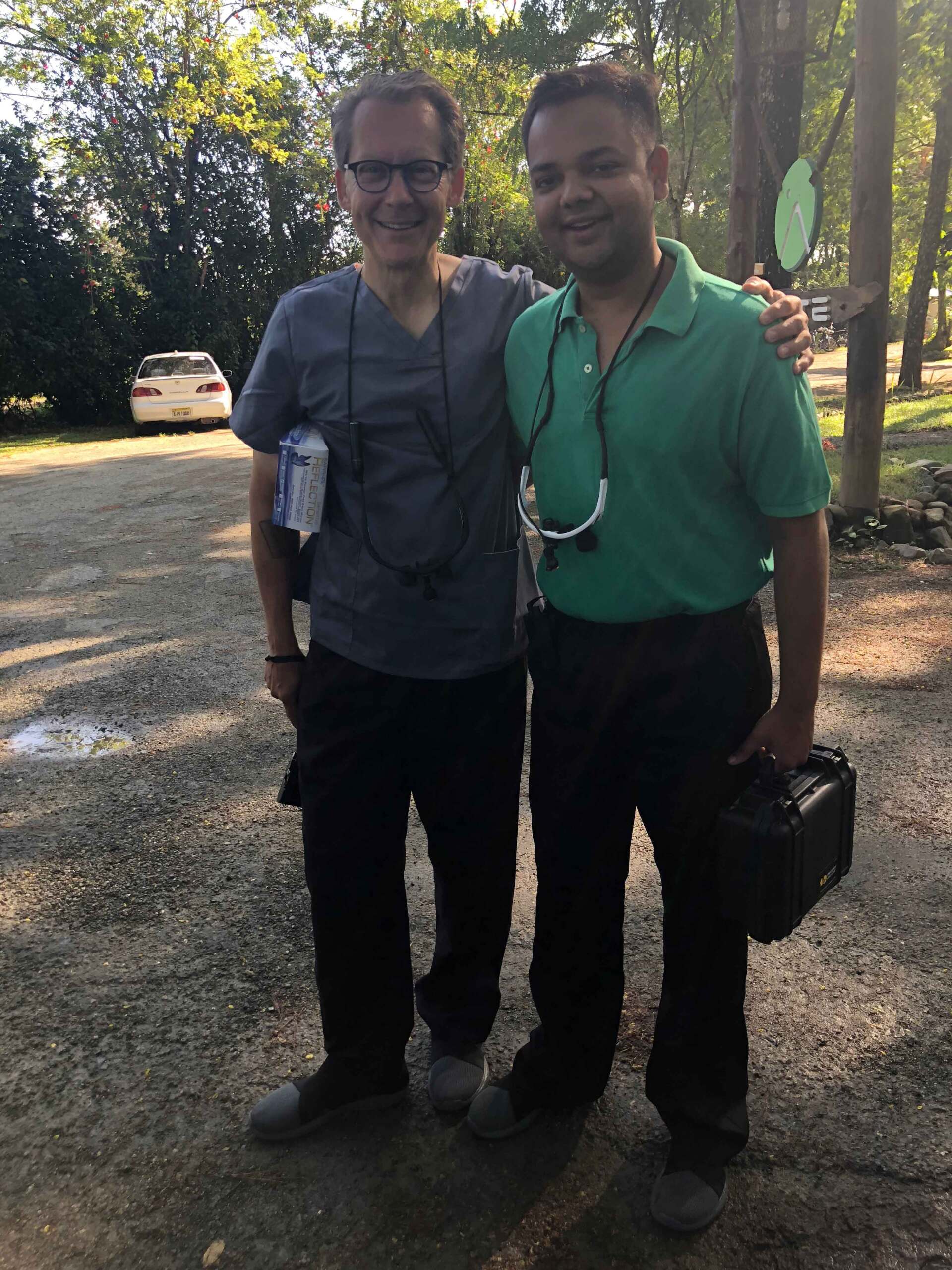 Two men standing next to each other with one wearing a green shirt