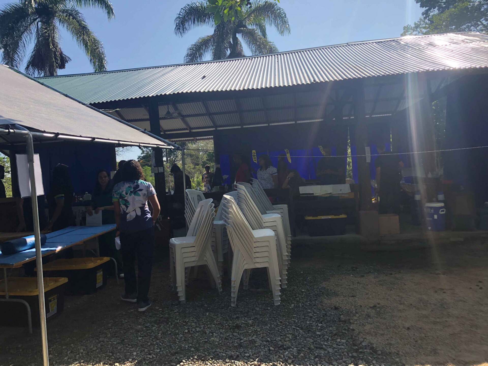 A group of people are standing outside of a building with tables and chairs.