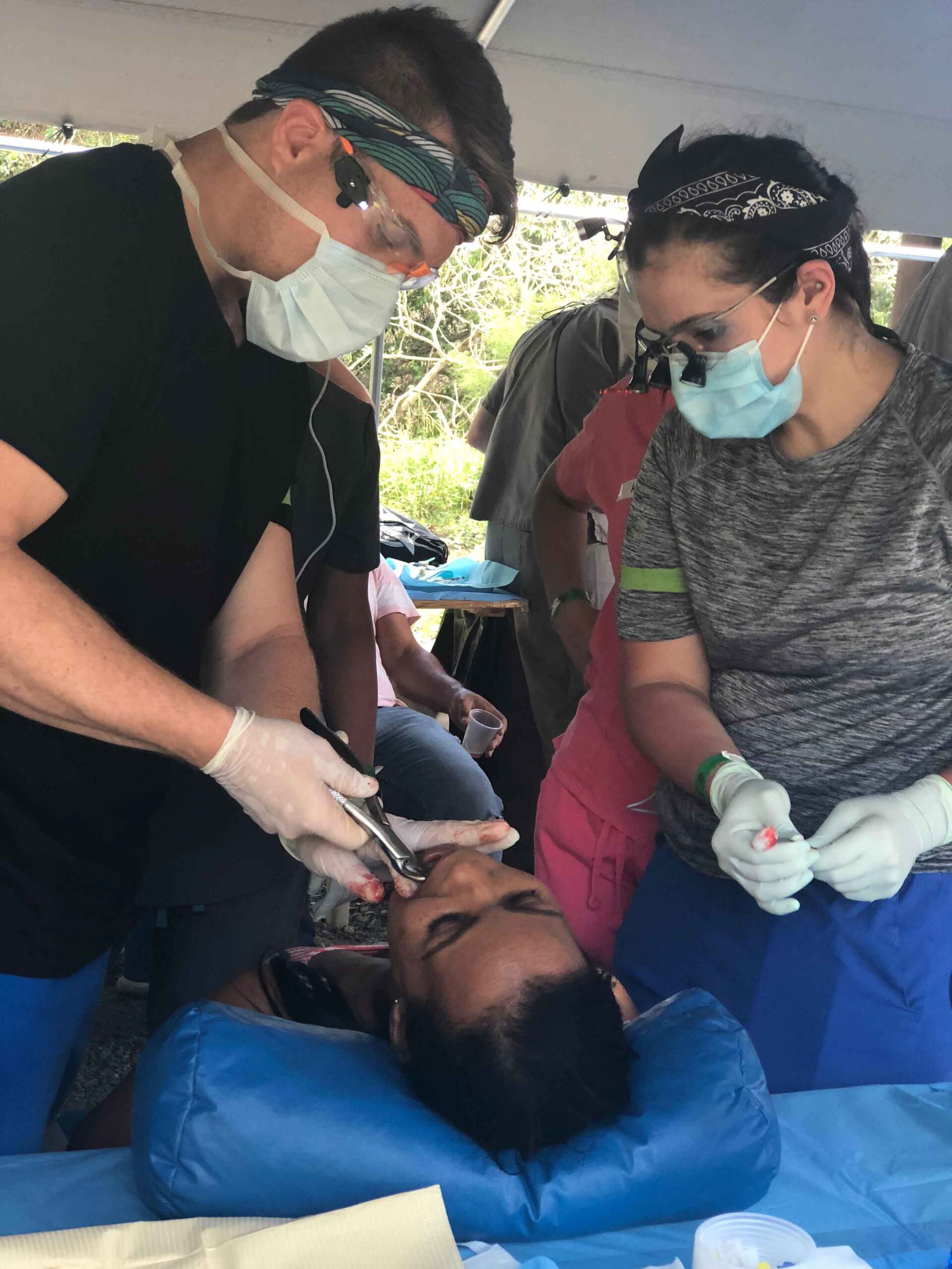 A man and a woman are working on a patient 's teeth.
