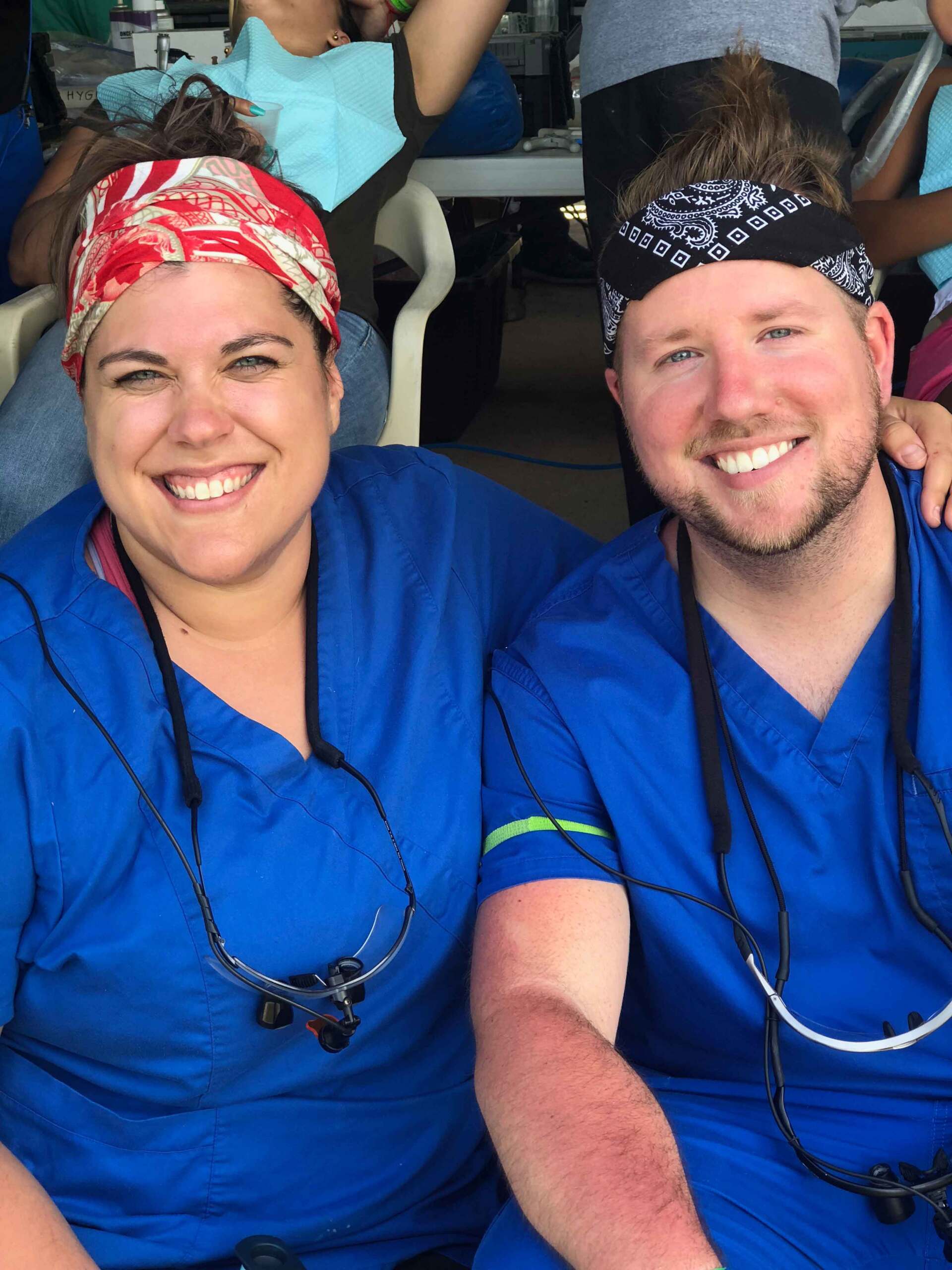 A man and a woman in blue scrubs are smiling for the camera