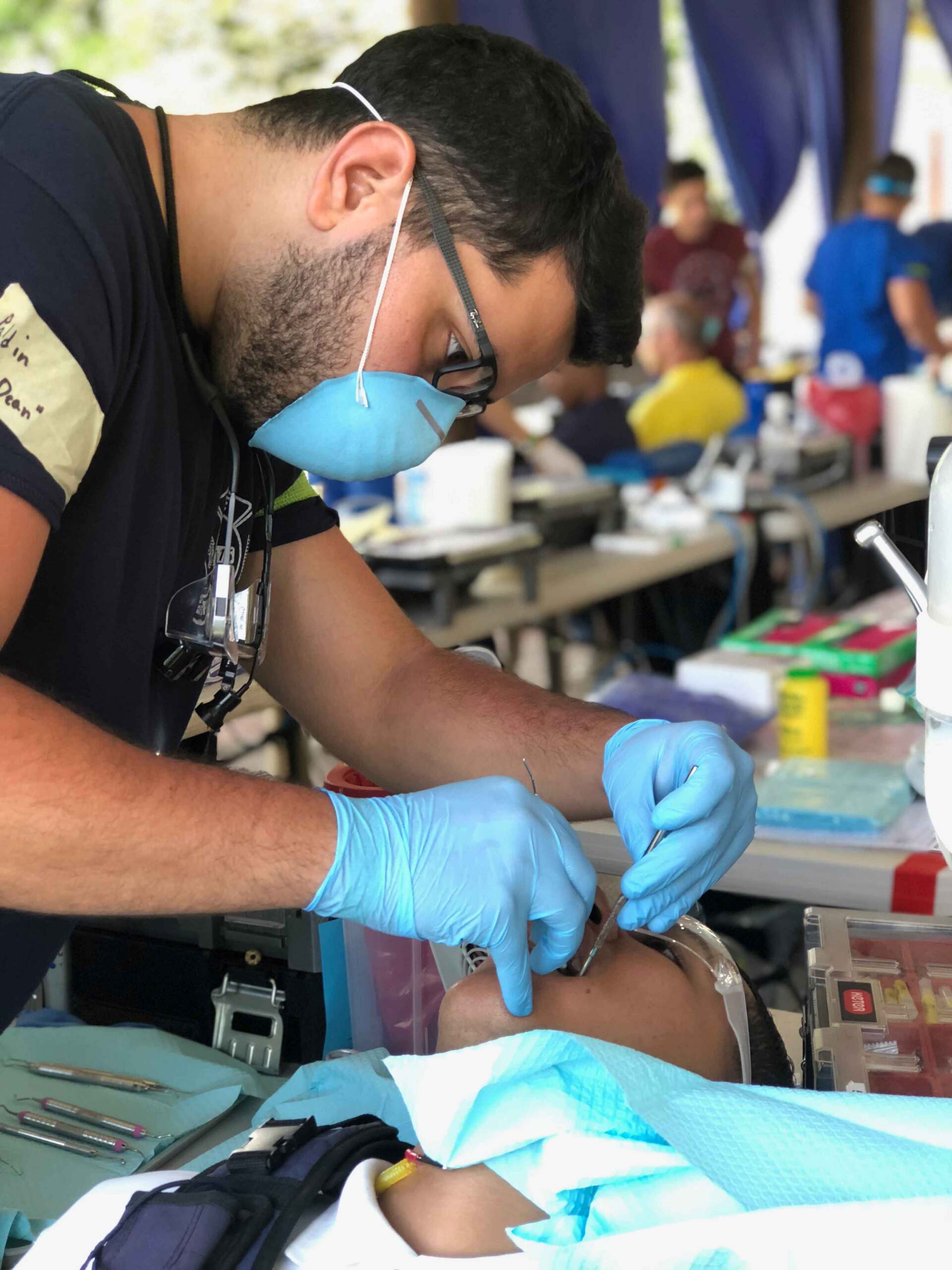 A man wearing a mask and gloves is working on a child 's teeth.