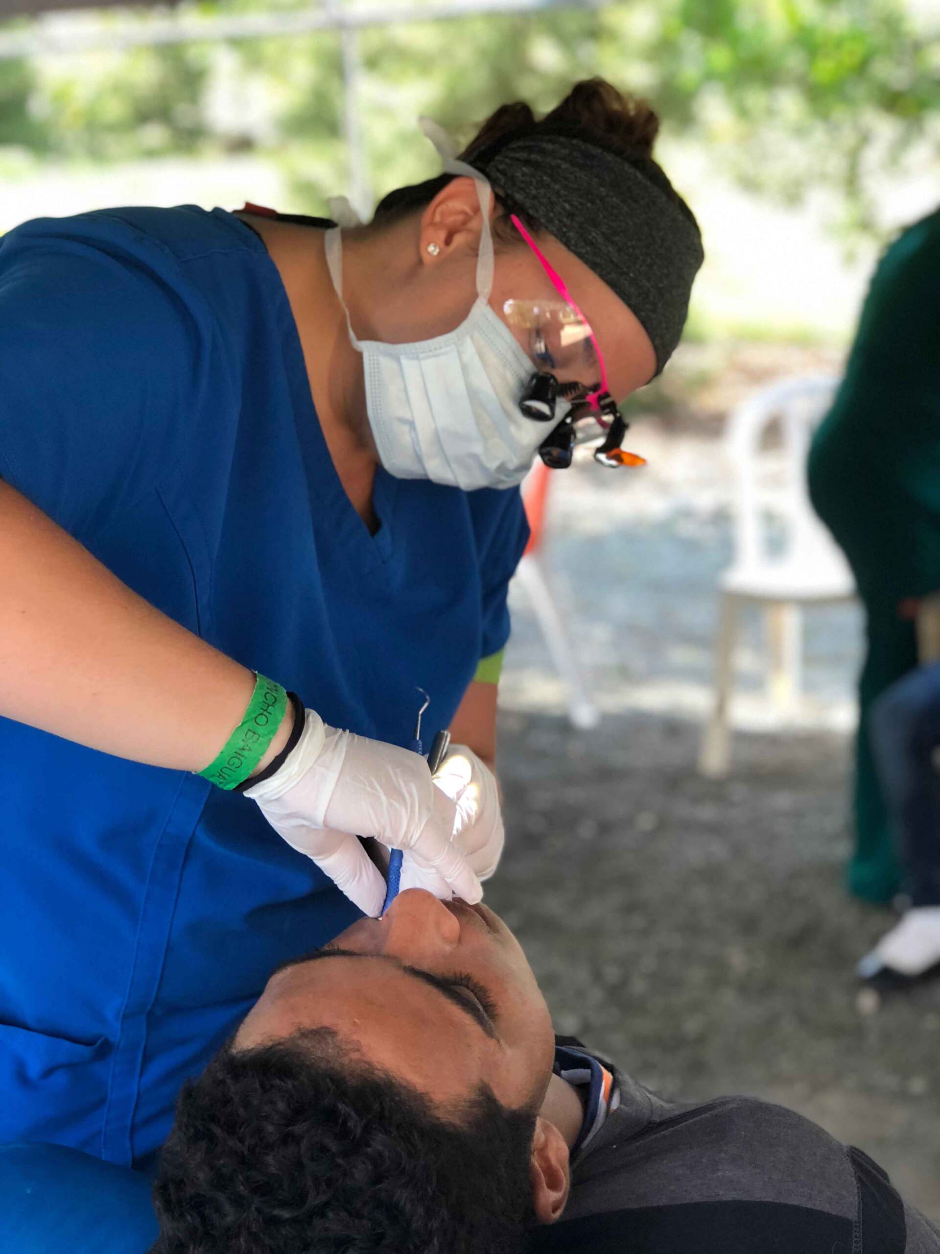 A woman wearing a mask is examining a man 's teeth