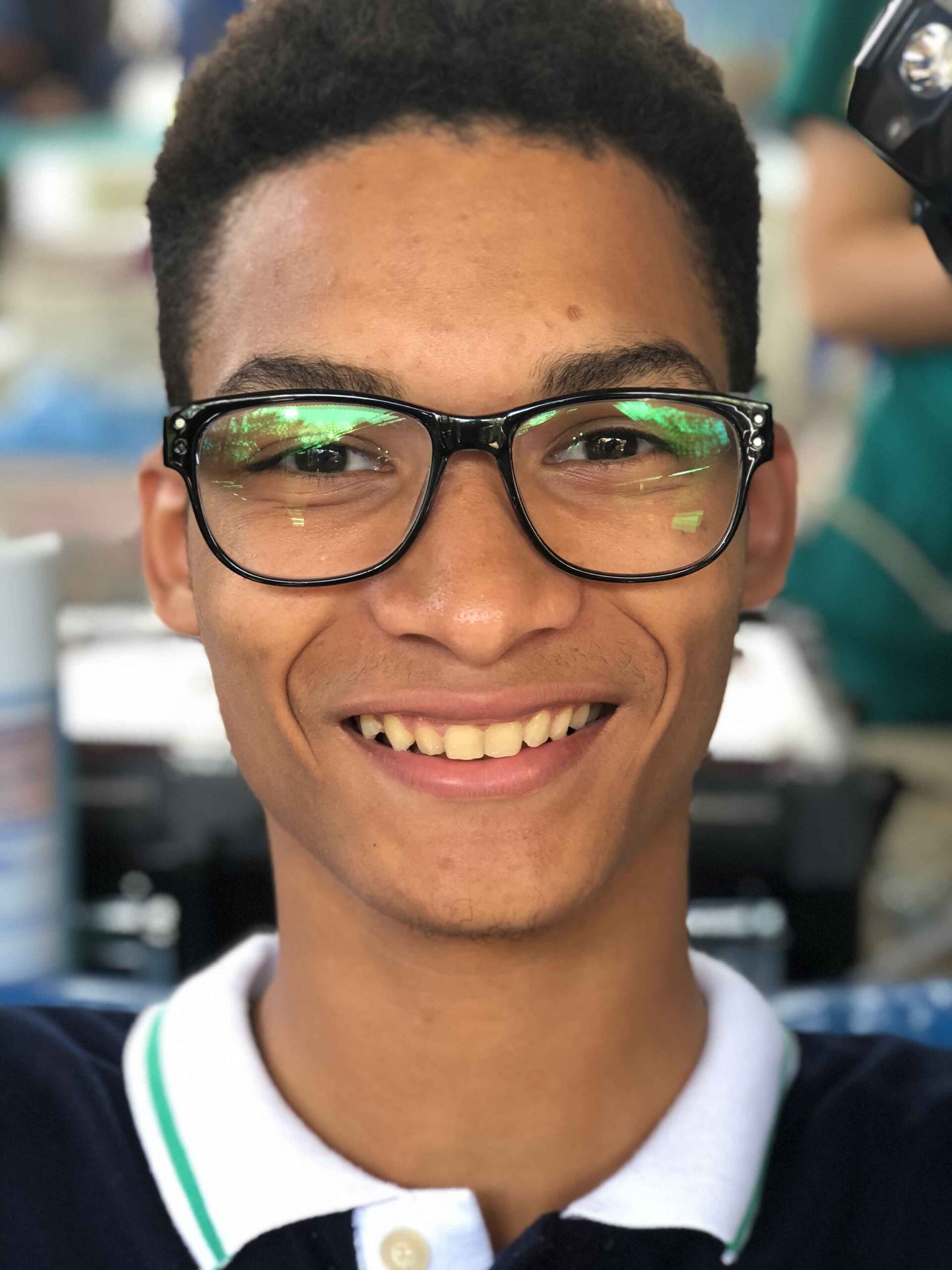 A young man wearing glasses is smiling for the camera