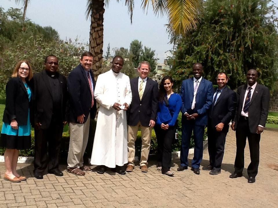 A group of people posing for a picture in front of a palm tree