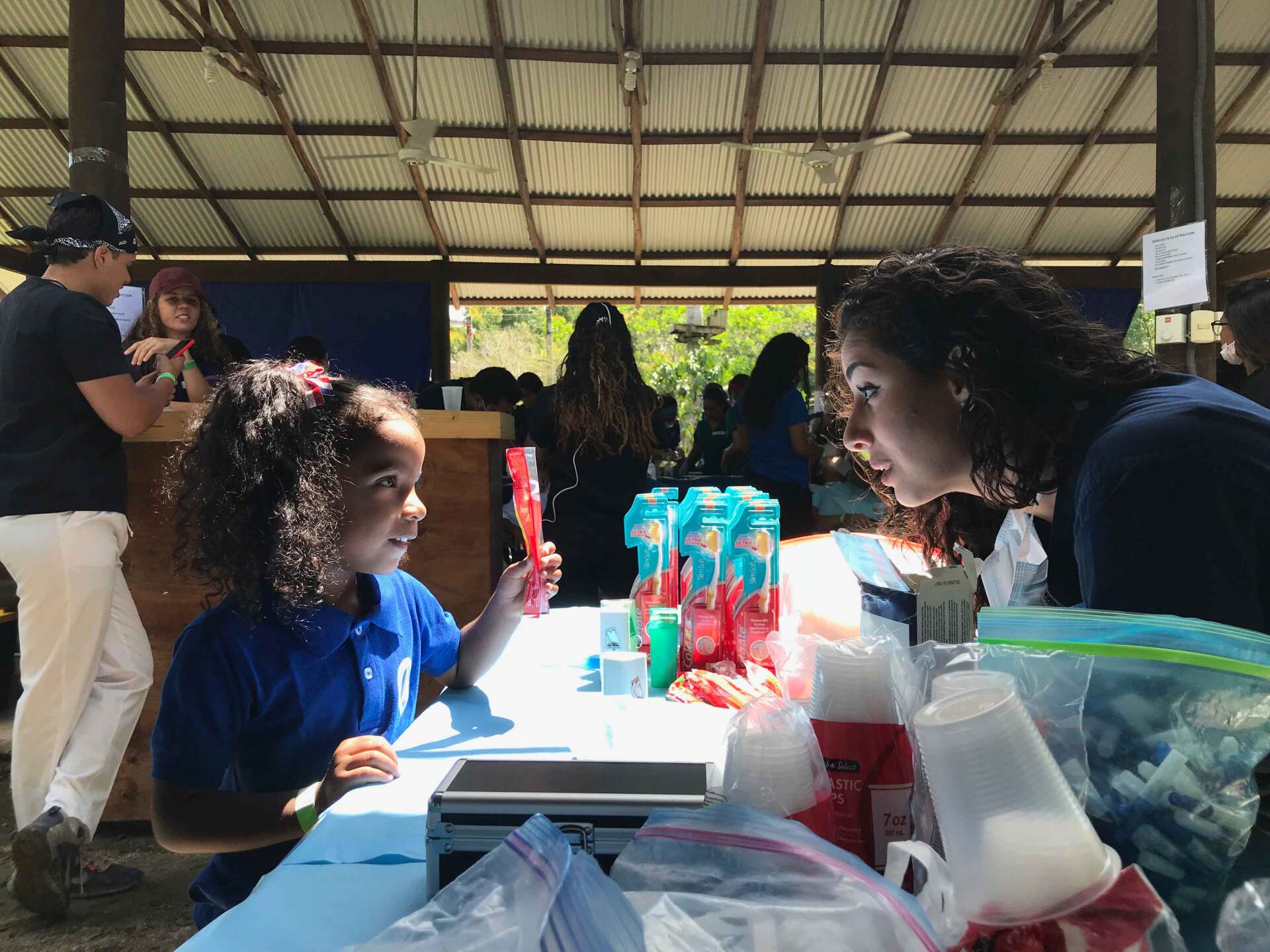 A woman is talking to a little girl who is sitting at a table.