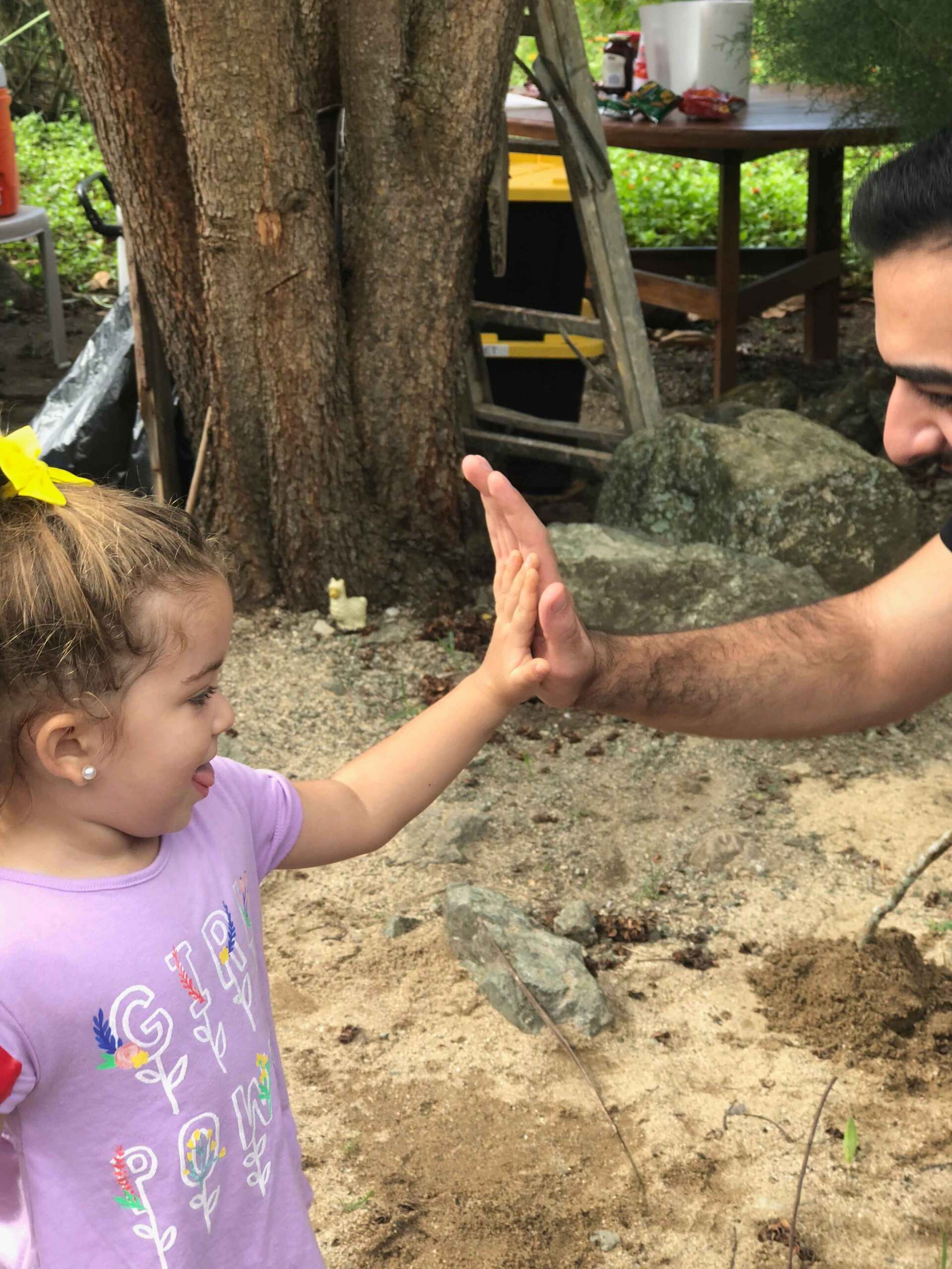 A little girl is giving a high five to a man.