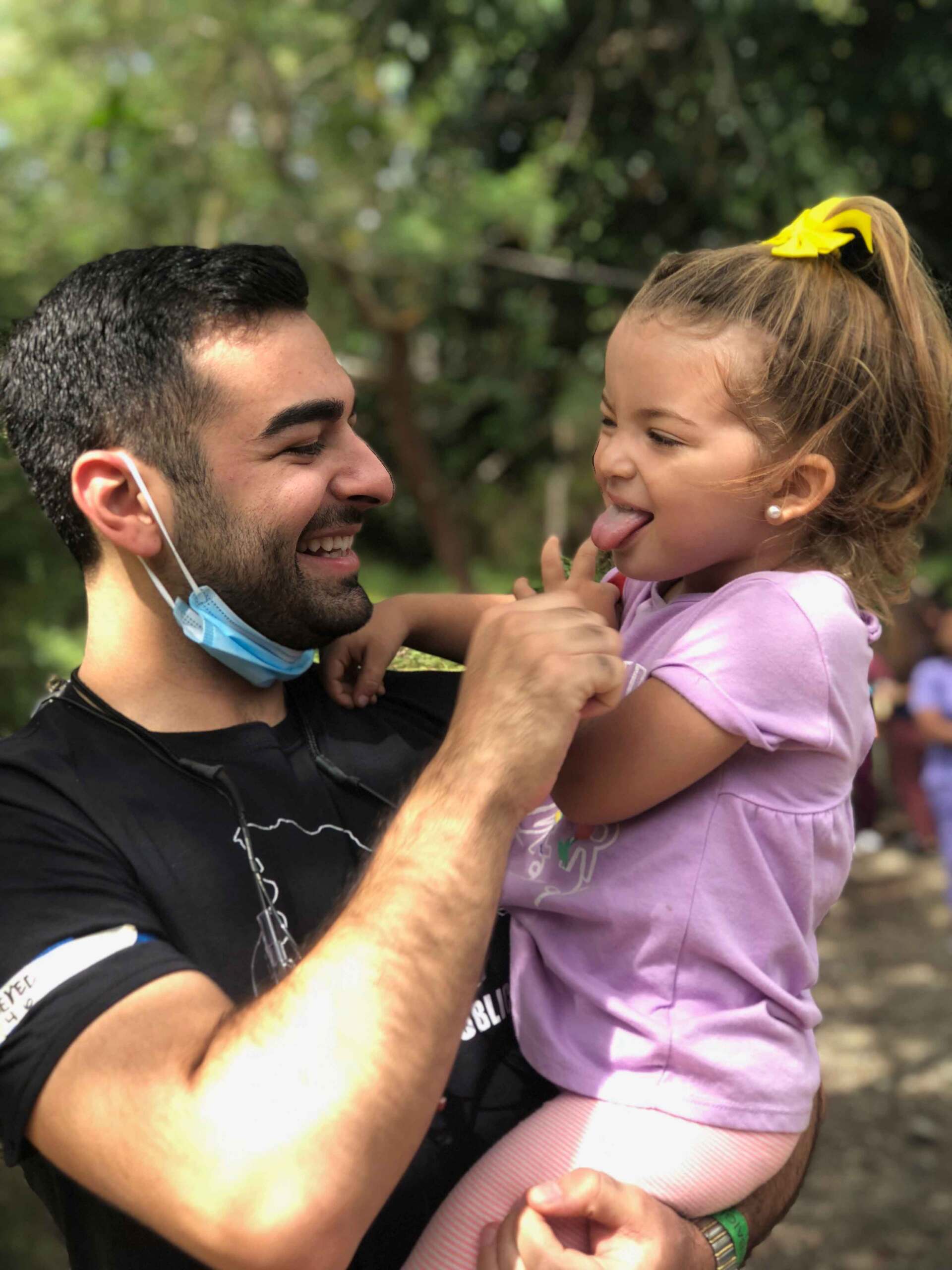 A man wearing a mask is holding a little girl in his arms.