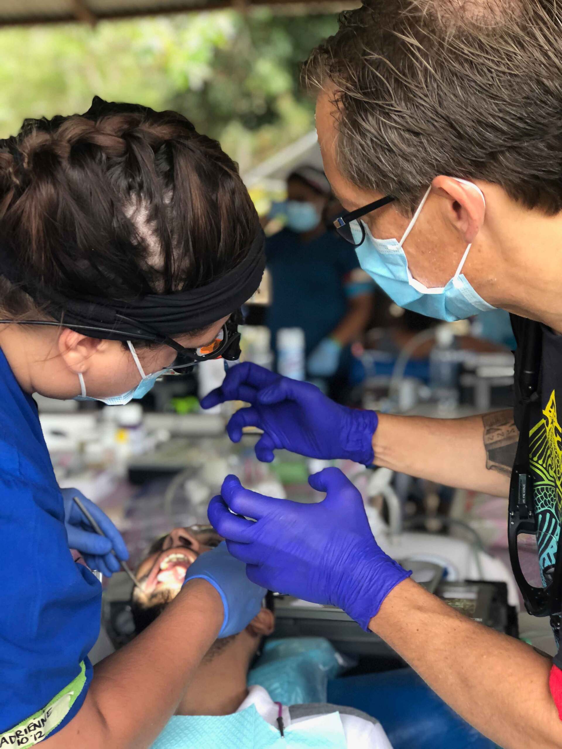 A man and a woman are working on a child 's teeth