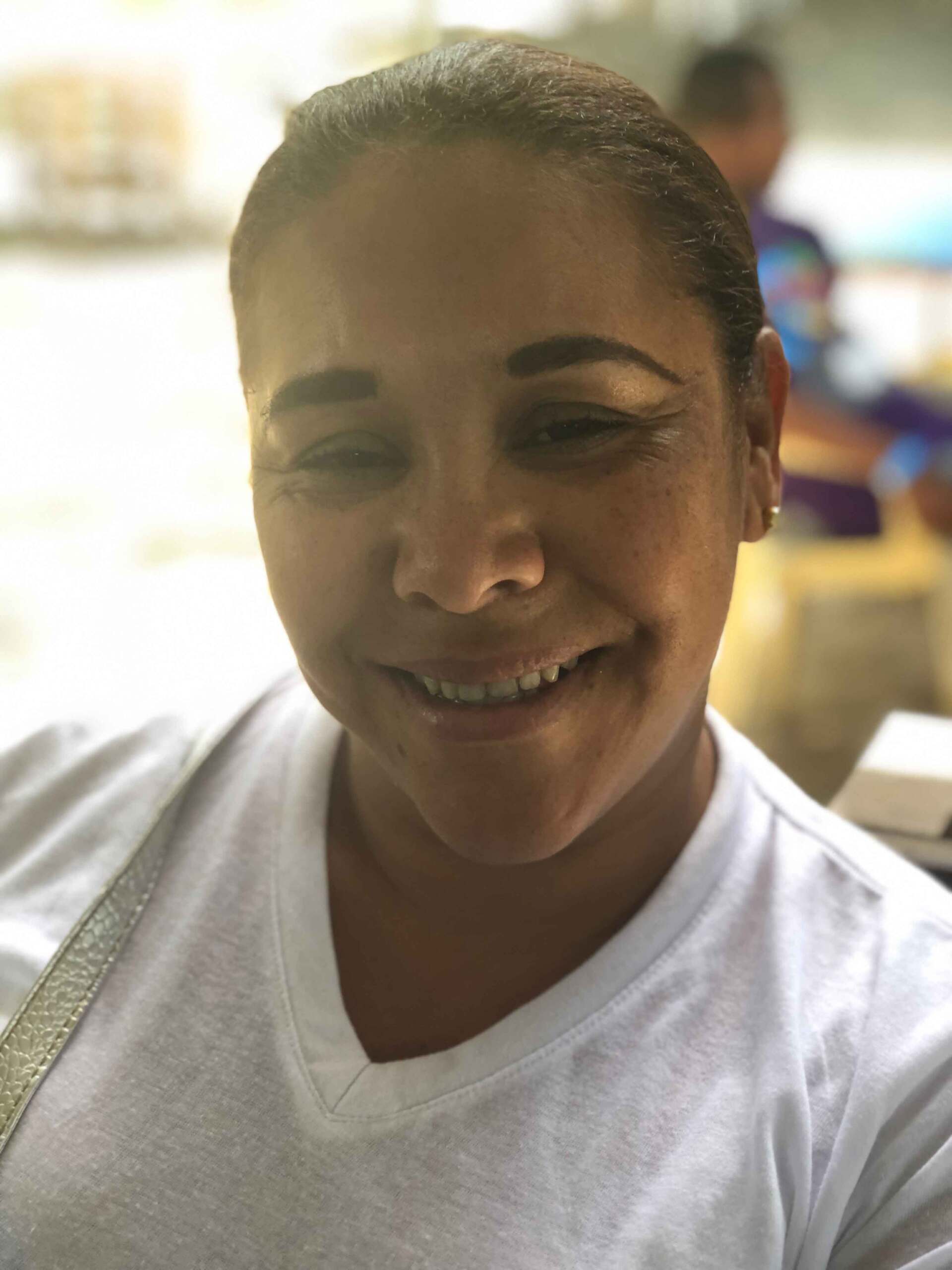 A woman in a white shirt is smiling for the camera.