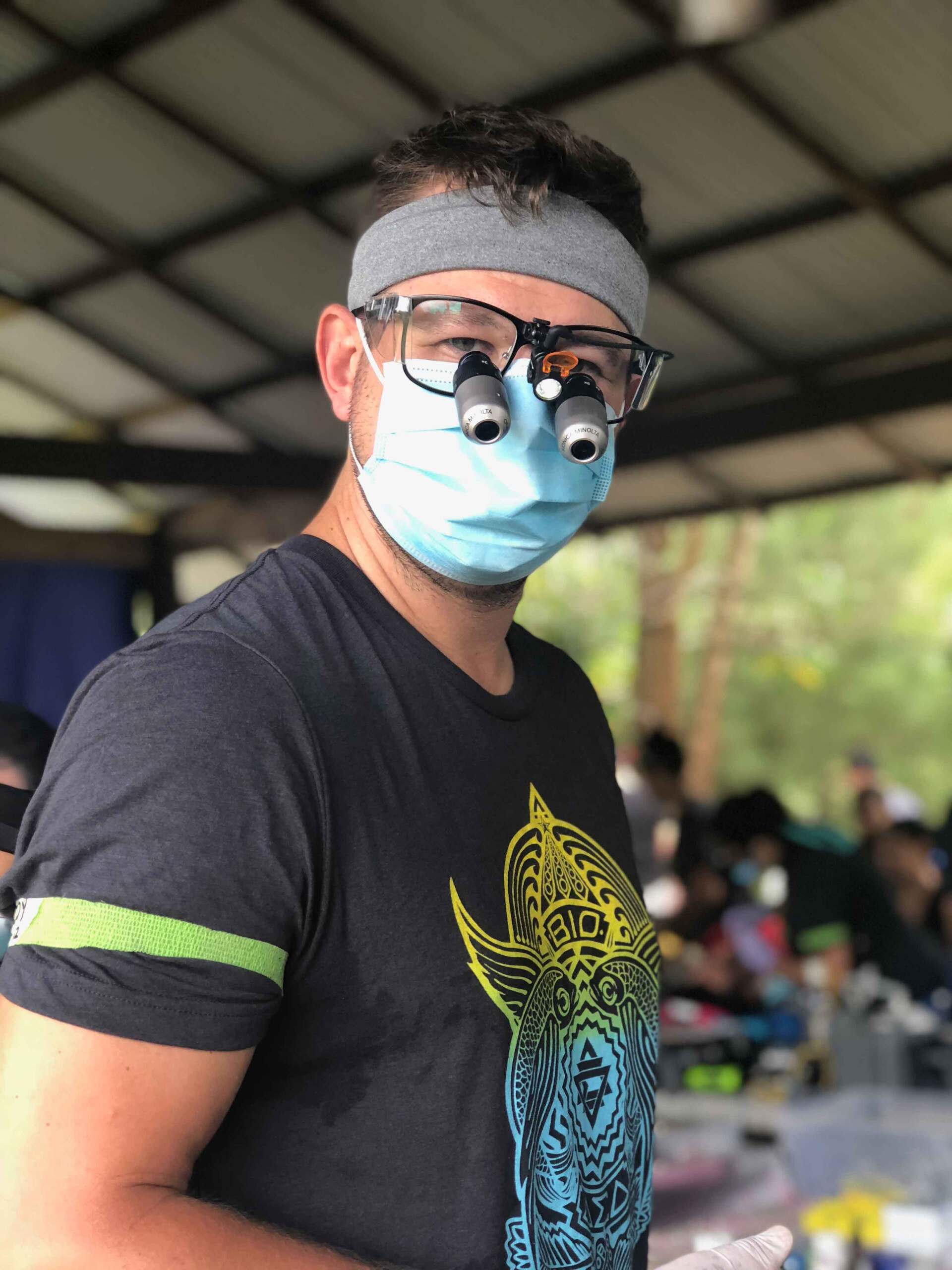 A man wearing a mask and glasses looks at the camera