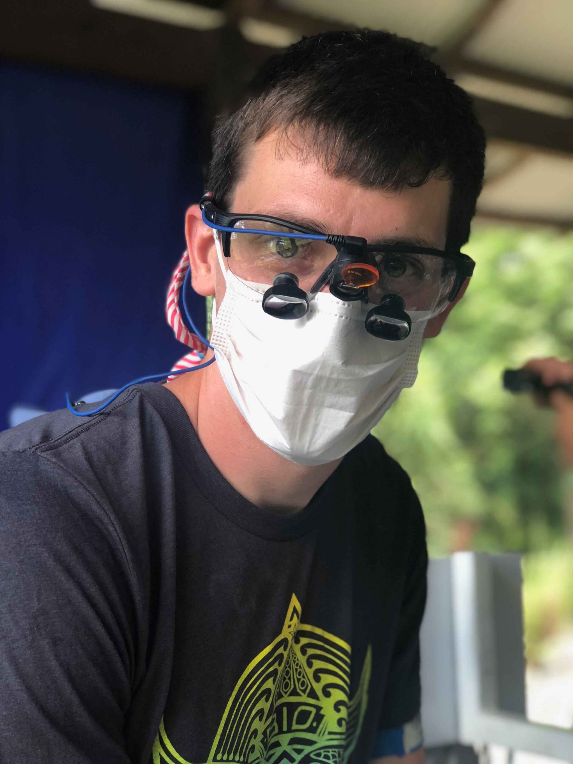 A man wearing a mask and glasses looks at the camera
