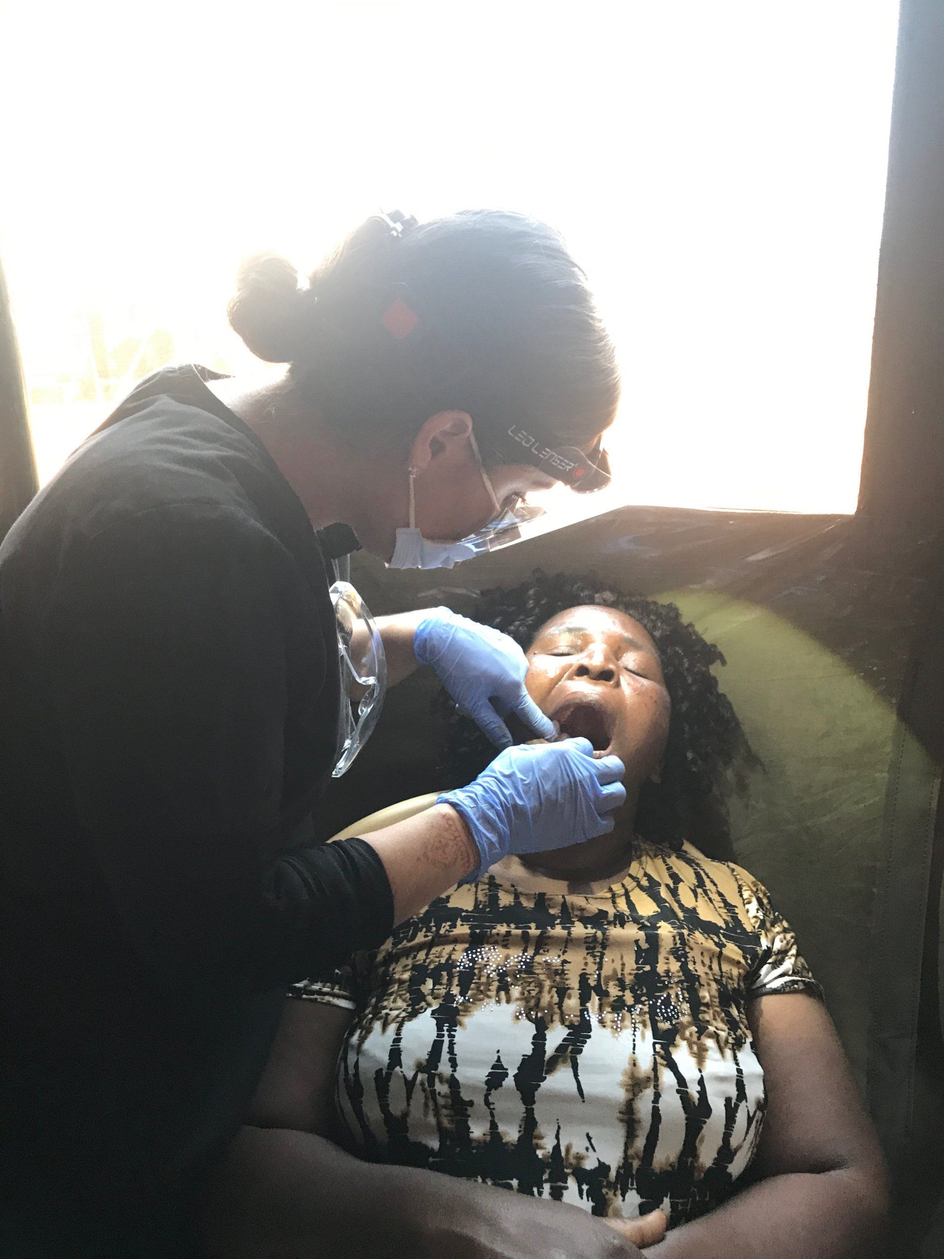 A woman is getting her teeth examined by a dentist.