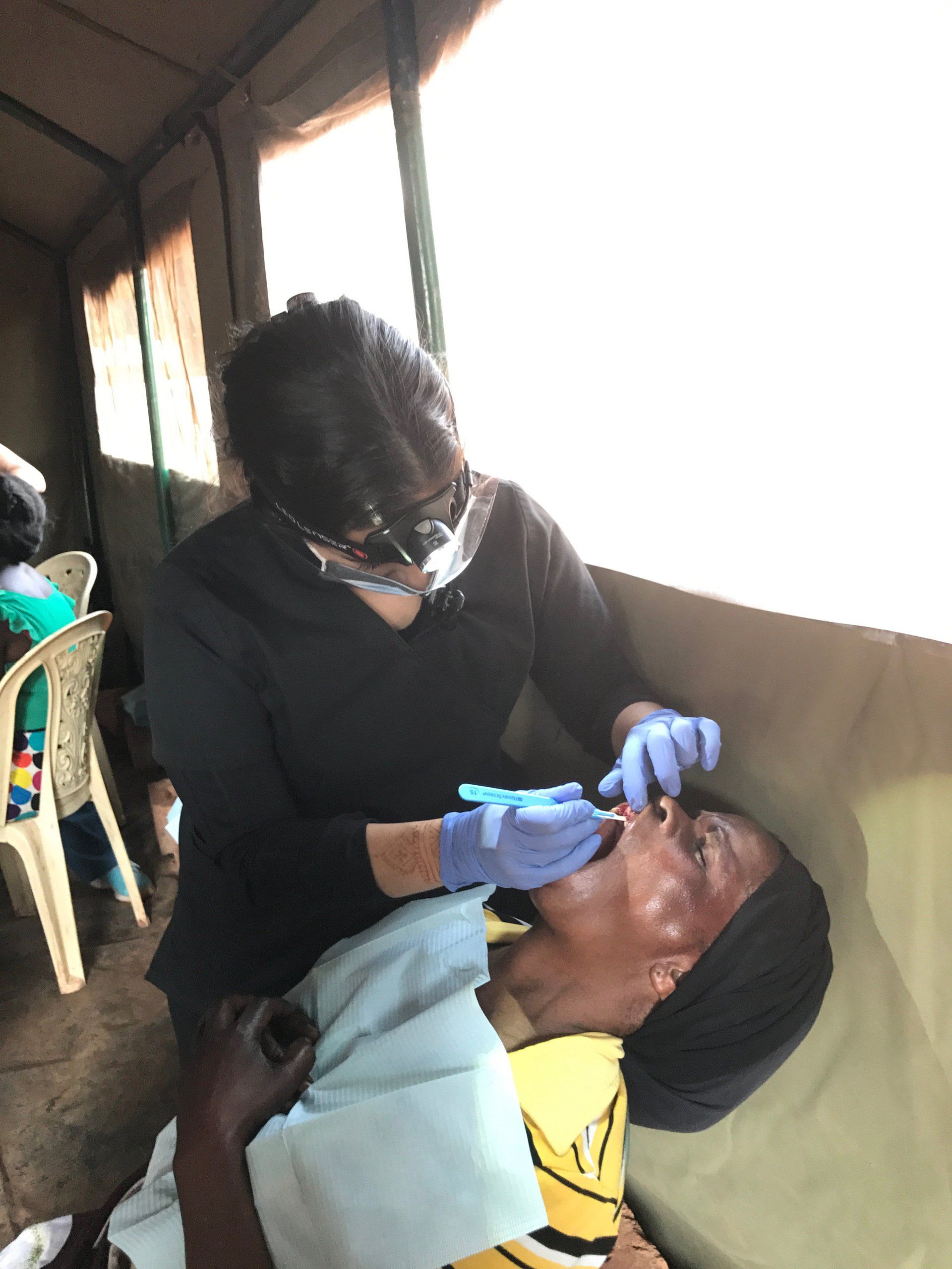 A dentist is examining a patient 's teeth in a tent.