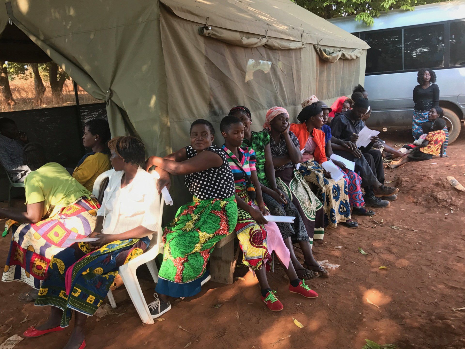 A group of women are sitting outside of a tent.