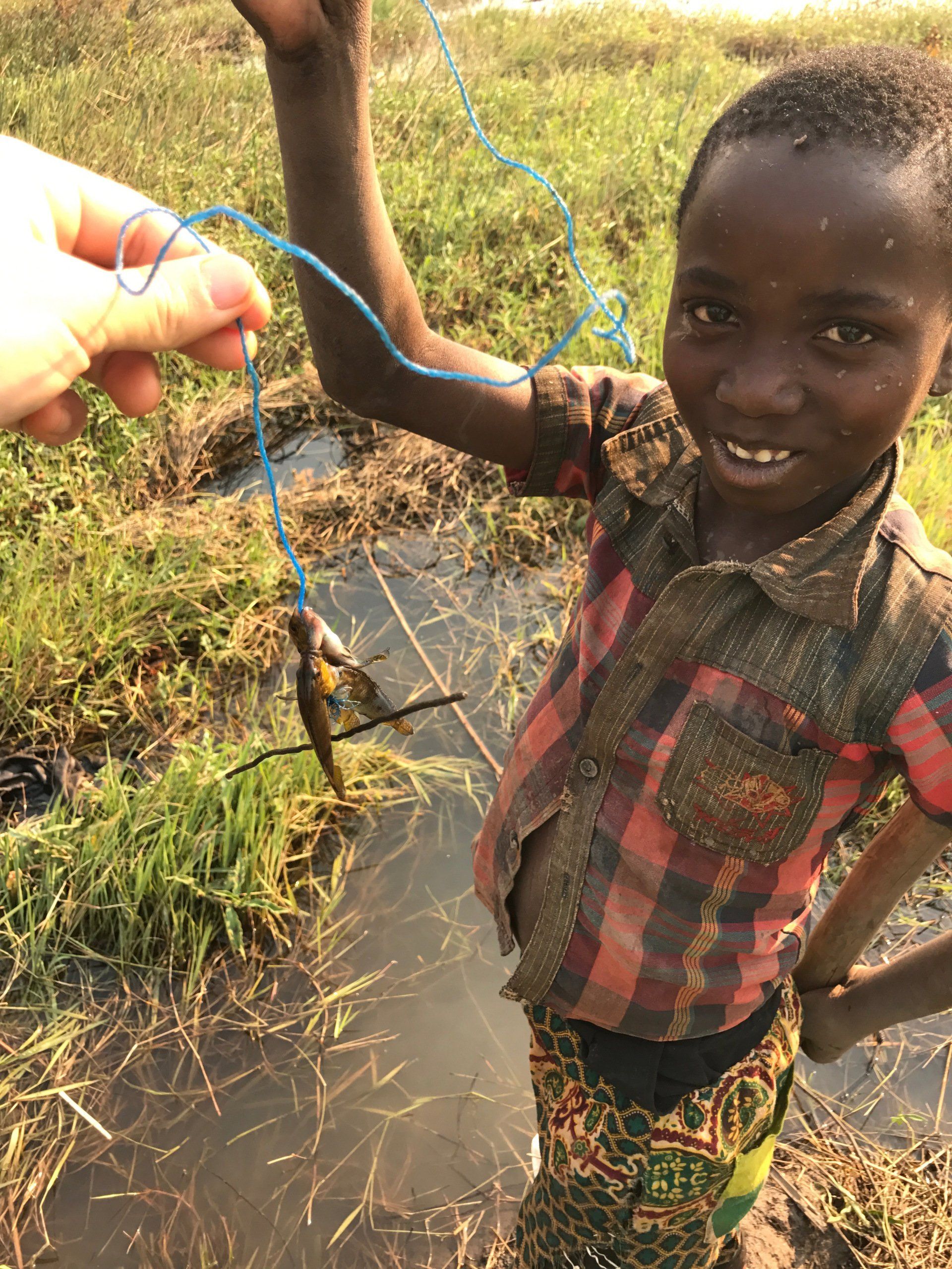 A young boy is holding a fish in his hand