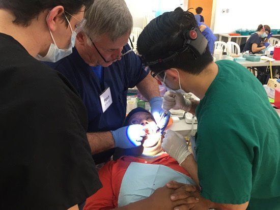 A group of dentists are working on a patient 's teeth