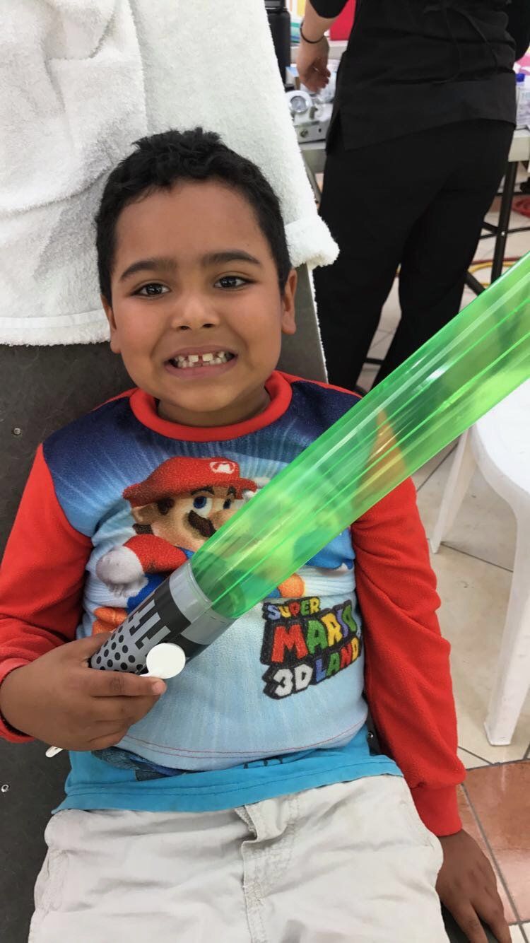 A young boy wearing a mario shirt is holding a green balloon