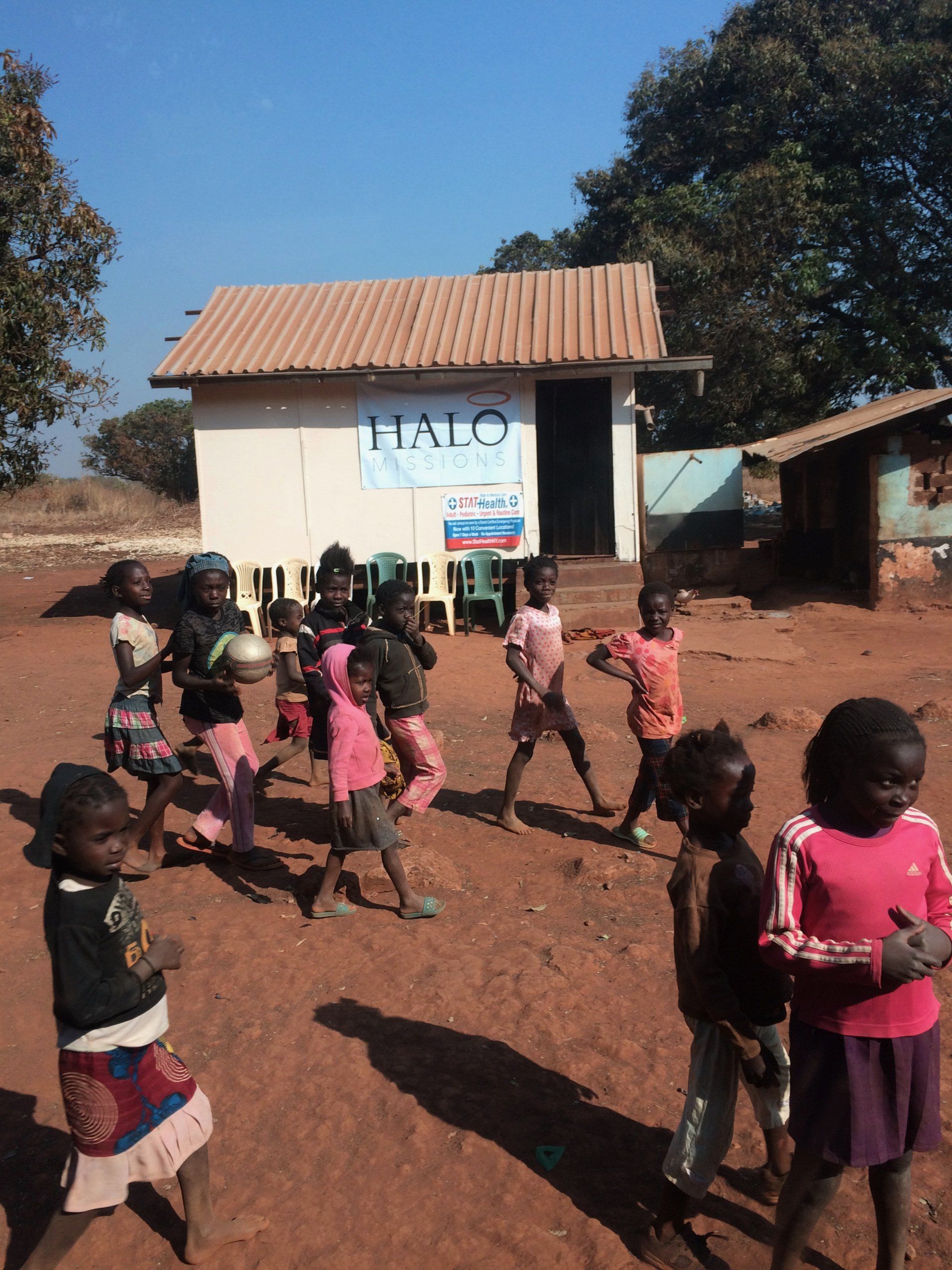 A group of children are playing in front of a building that says halo