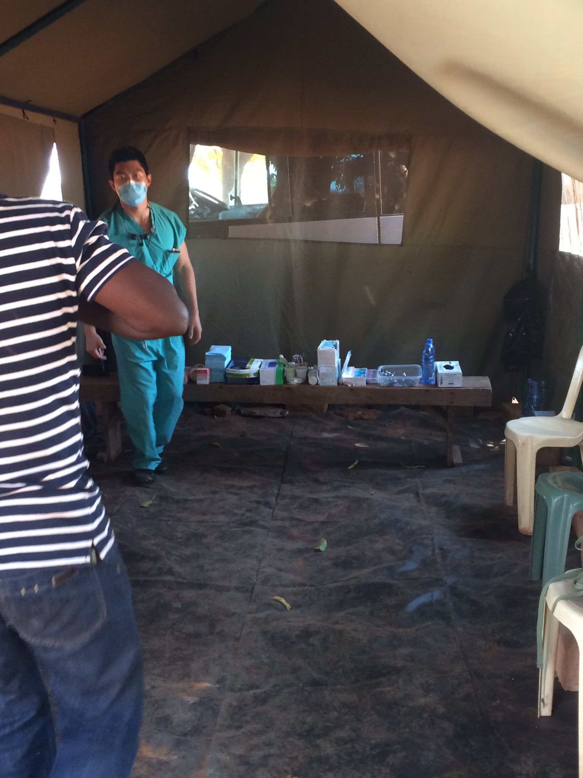 A man wearing a mask is standing in a tent