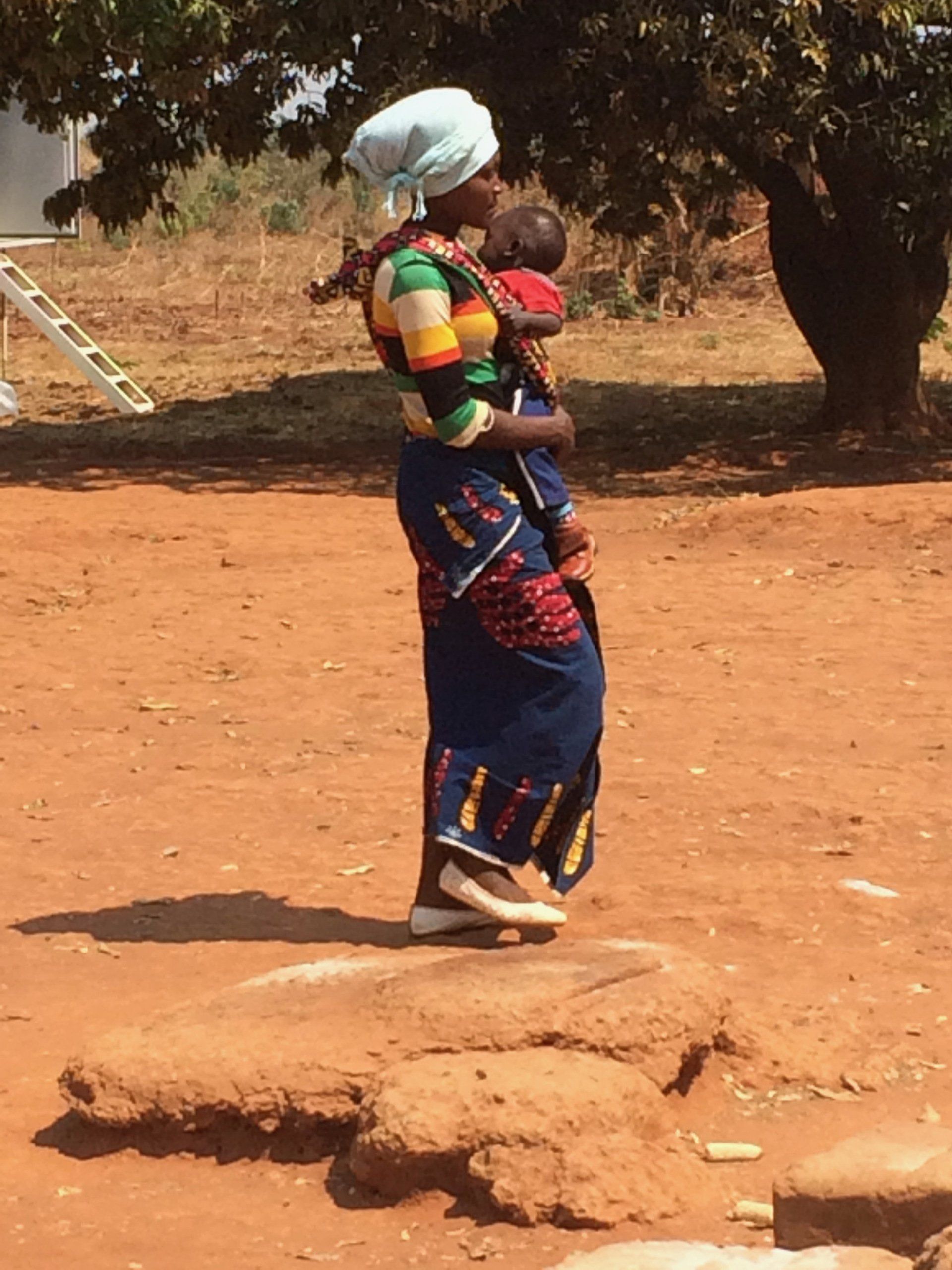 A woman is carrying a baby in her arms