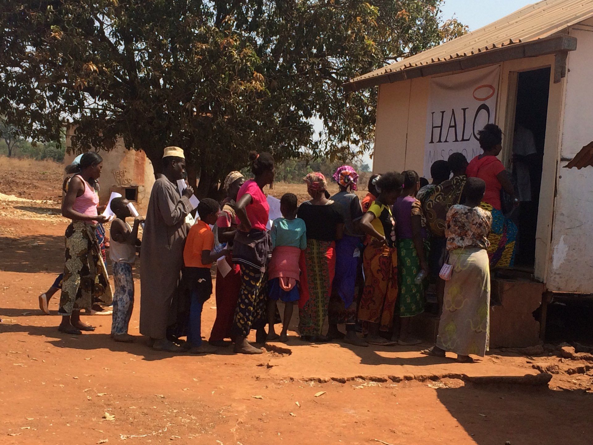 A group of people standing outside of a building that says halc