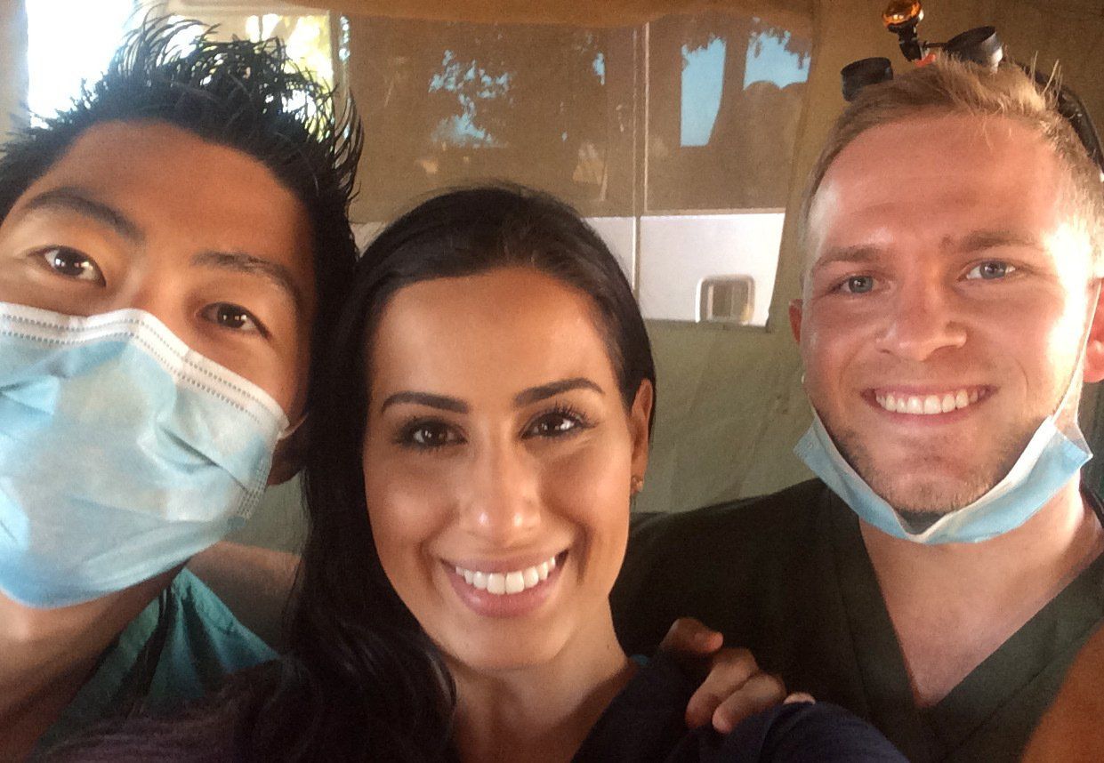 Two men and a woman wearing face masks are posing for a picture.