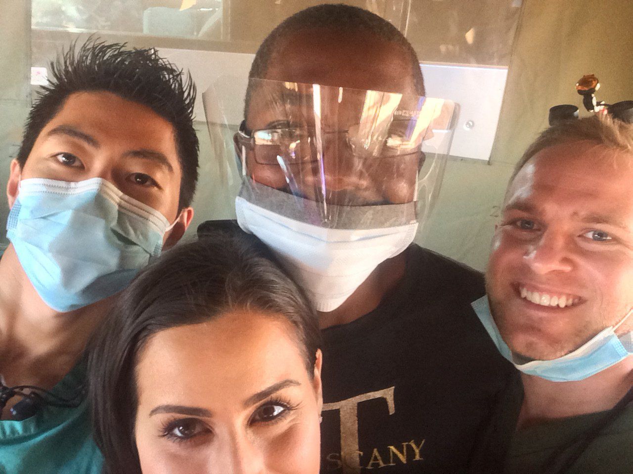 A group of people wearing face masks are posing for a picture