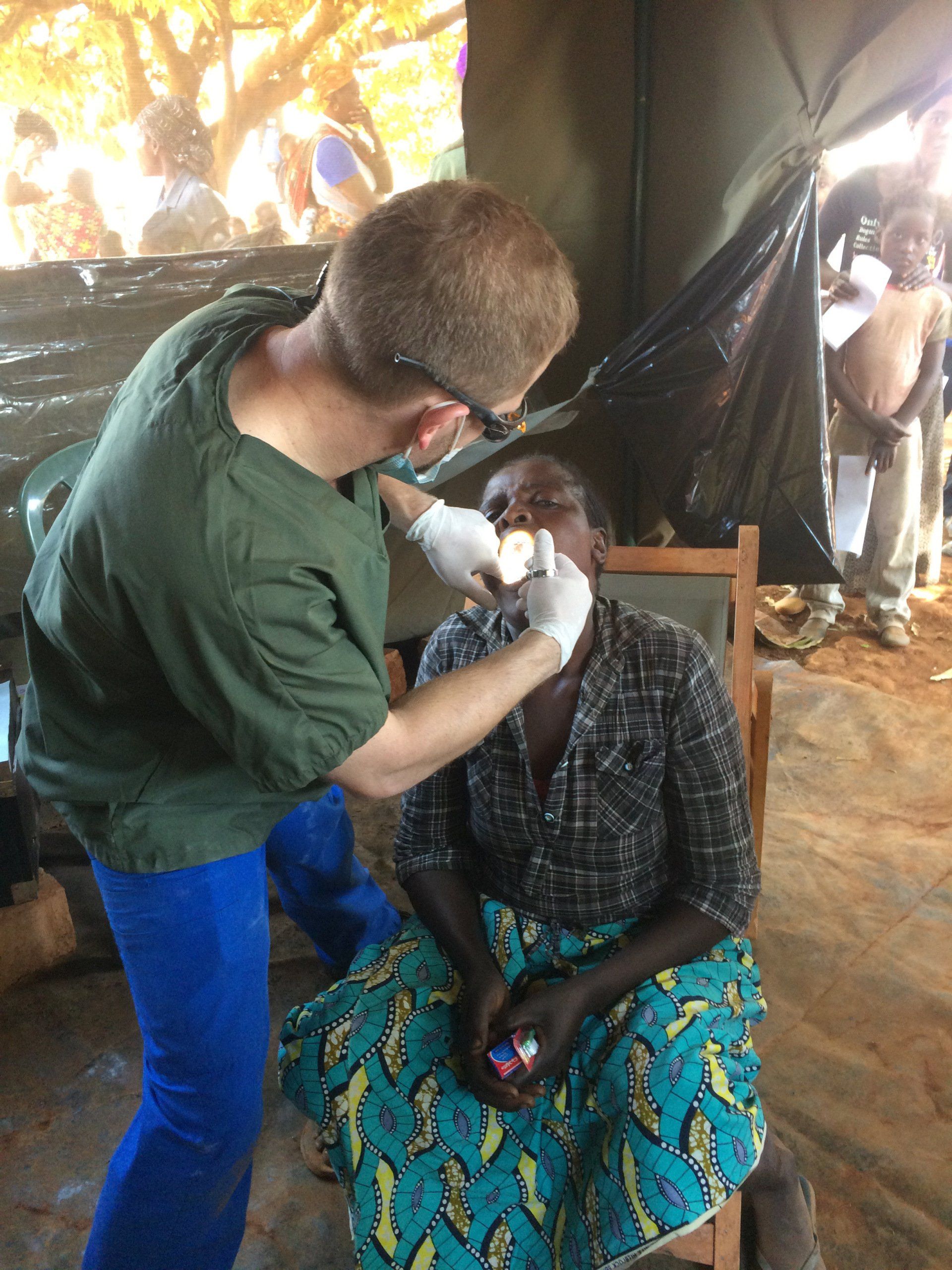 A man is examining a woman 's face while she sits in a chair