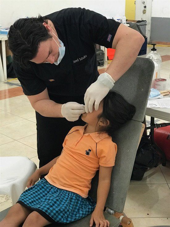 A little girl is getting her teeth examined by a dentist
