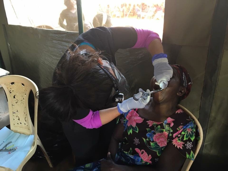A woman is getting her teeth examined by a dentist in a tent.