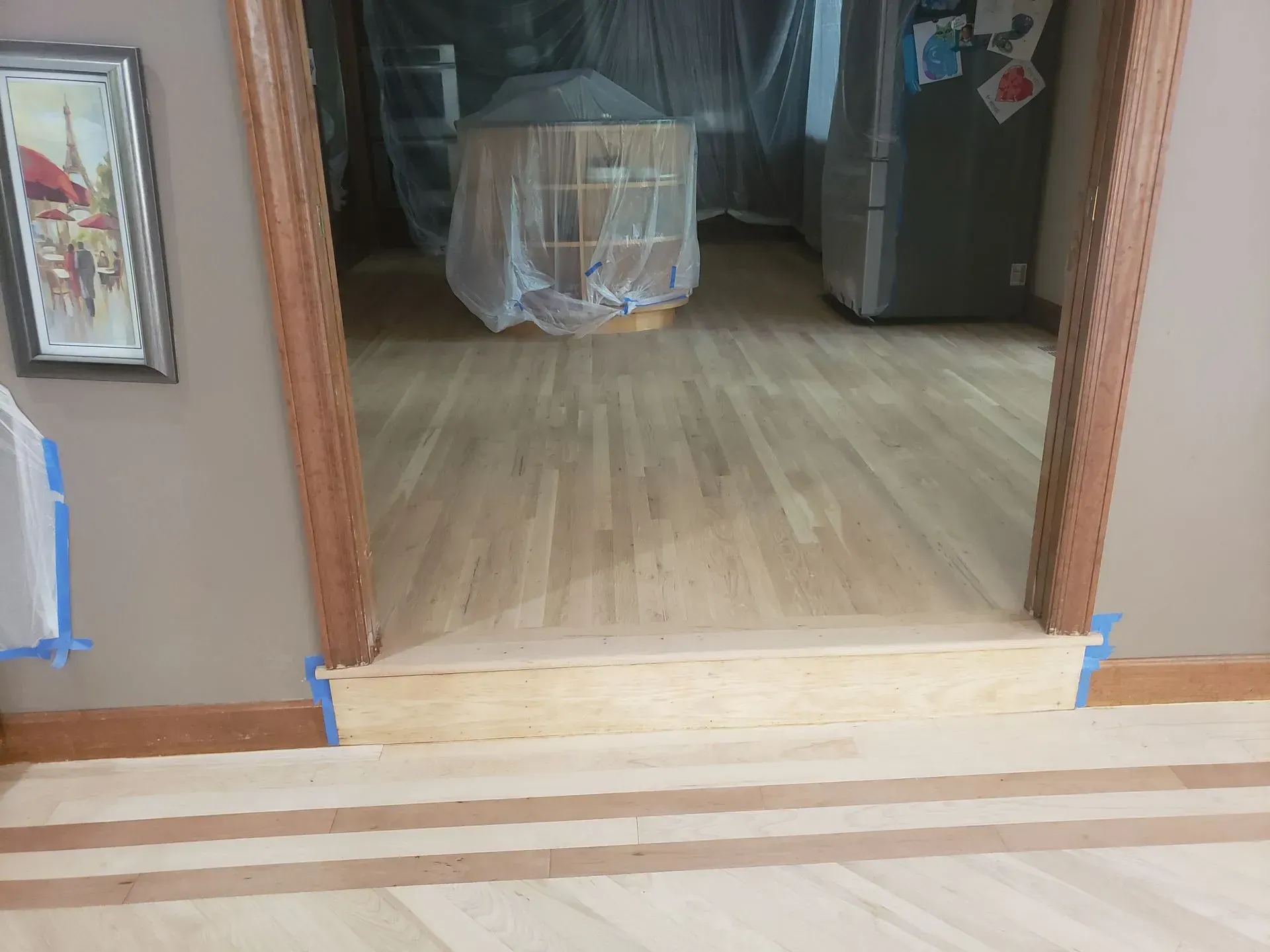 View of doorway with a step up; newly refinished hardwood floor.