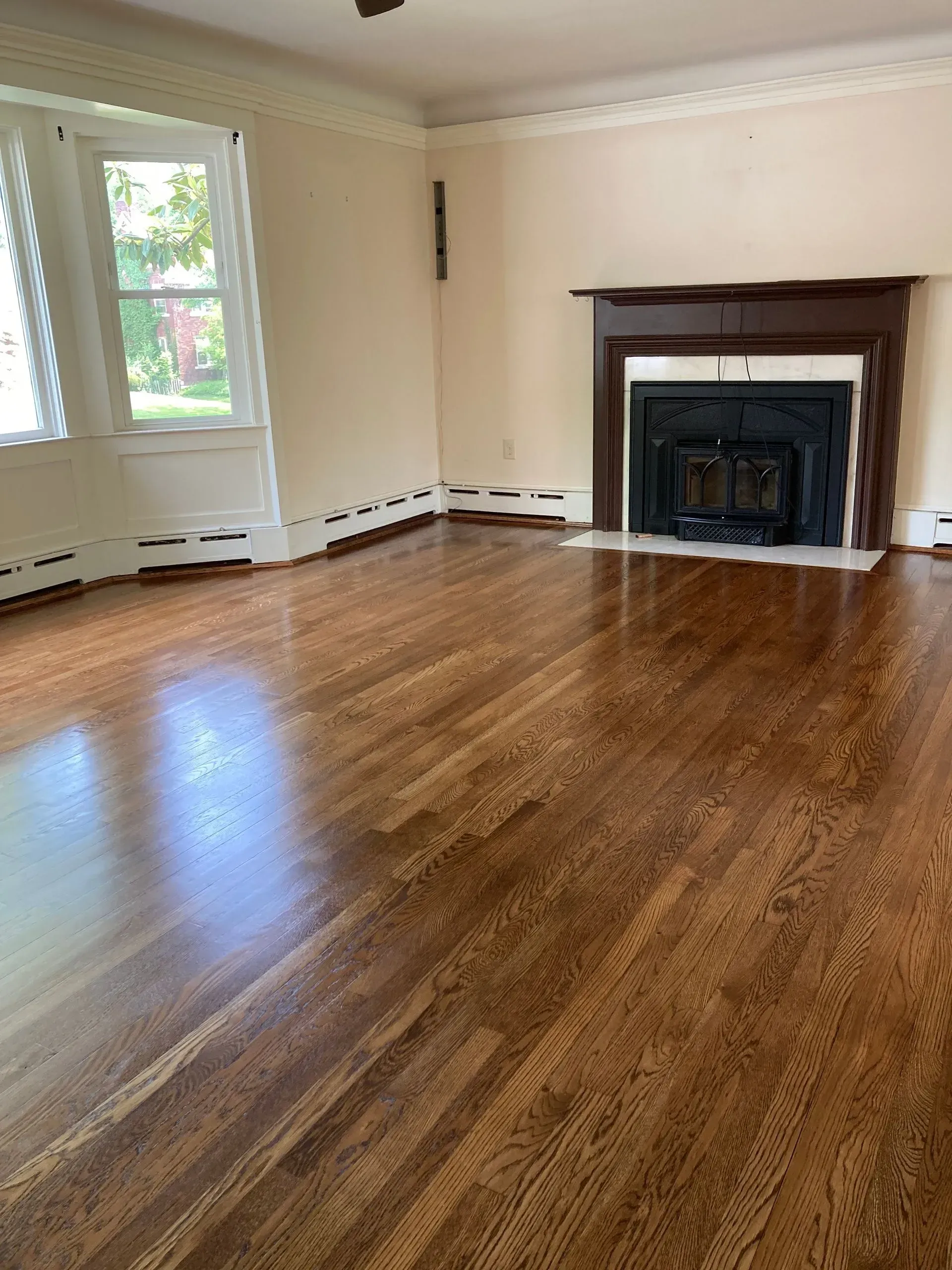 Empty living room with wood floors, fireplace, and window.