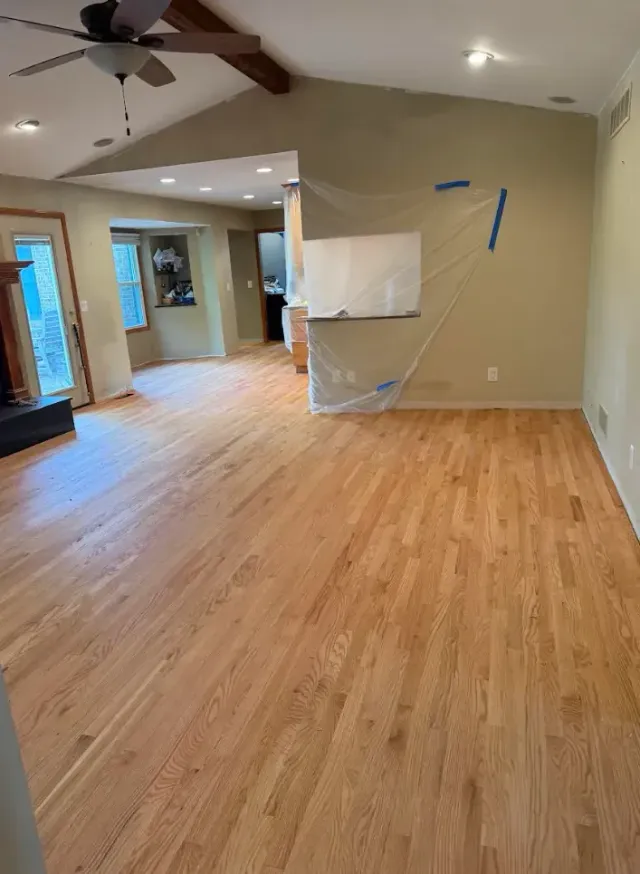 Person installing dark wood laminate flooring, kneeling.