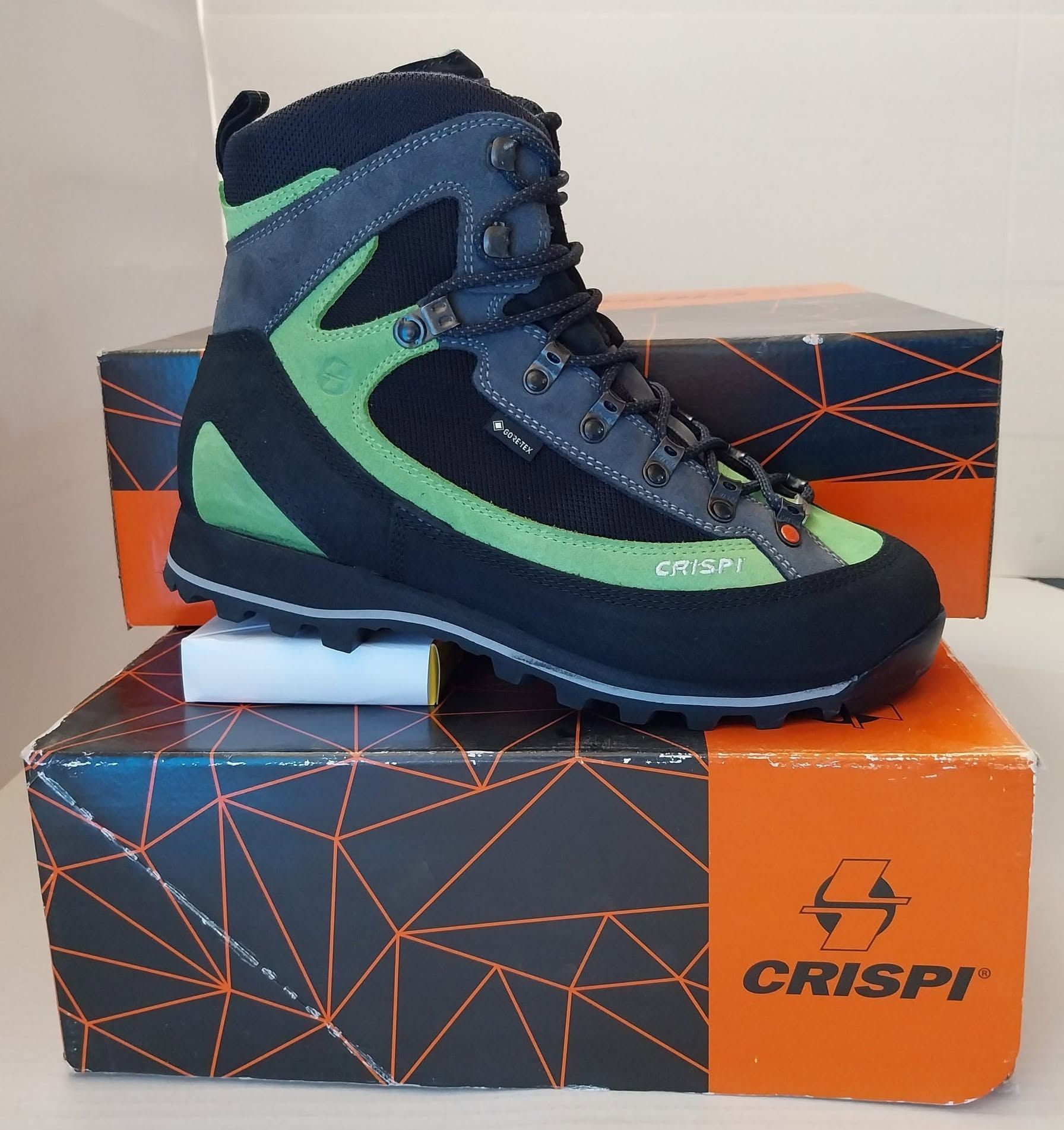 Scarponcino da trekking Crispi blu e verde su scatole di scarpe arancioni e nere