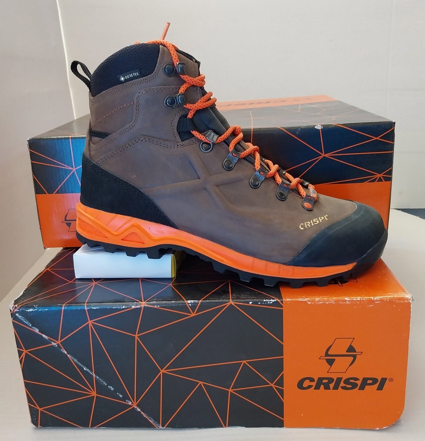 Scarponcino da trekking Crispi grigio e arancione su scatola coordinata con il logo del marchio.
