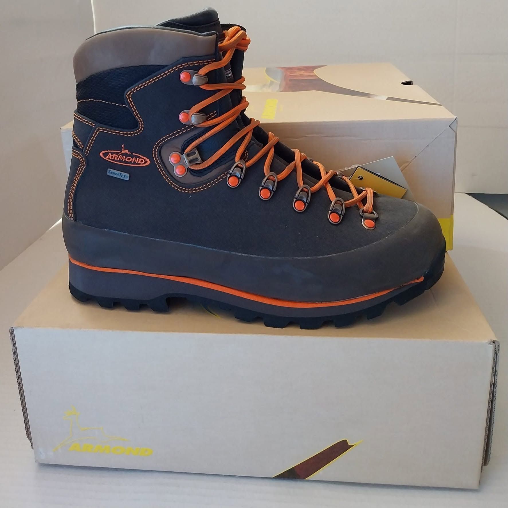 Scarponcino da trekking blu scuro con lacci arancioni, esposto su una scatola da scarpe.