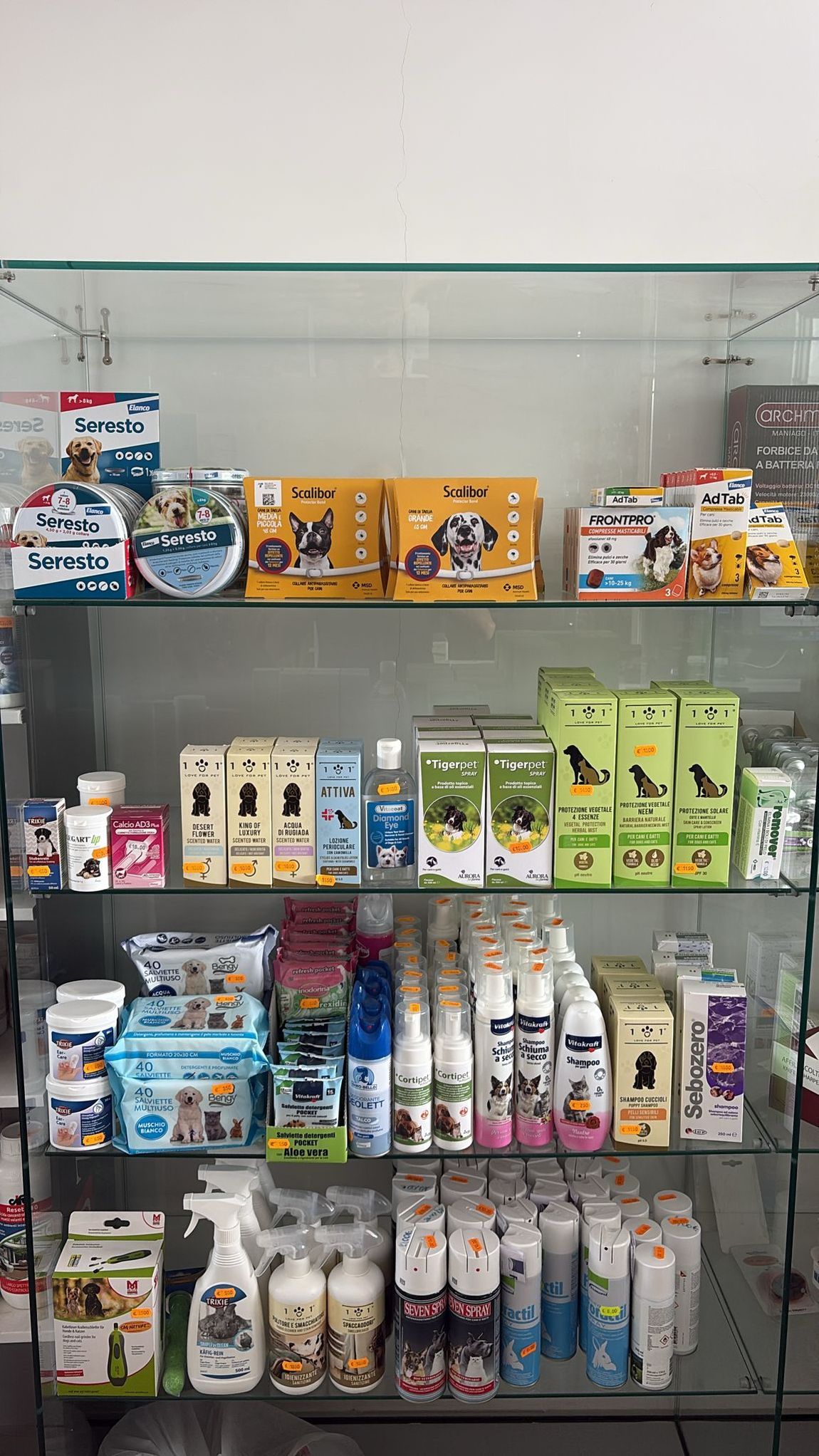 Scaffali con confezioni assortite di cibo e snack per animali domestici, disposte in un espositore di negozio.