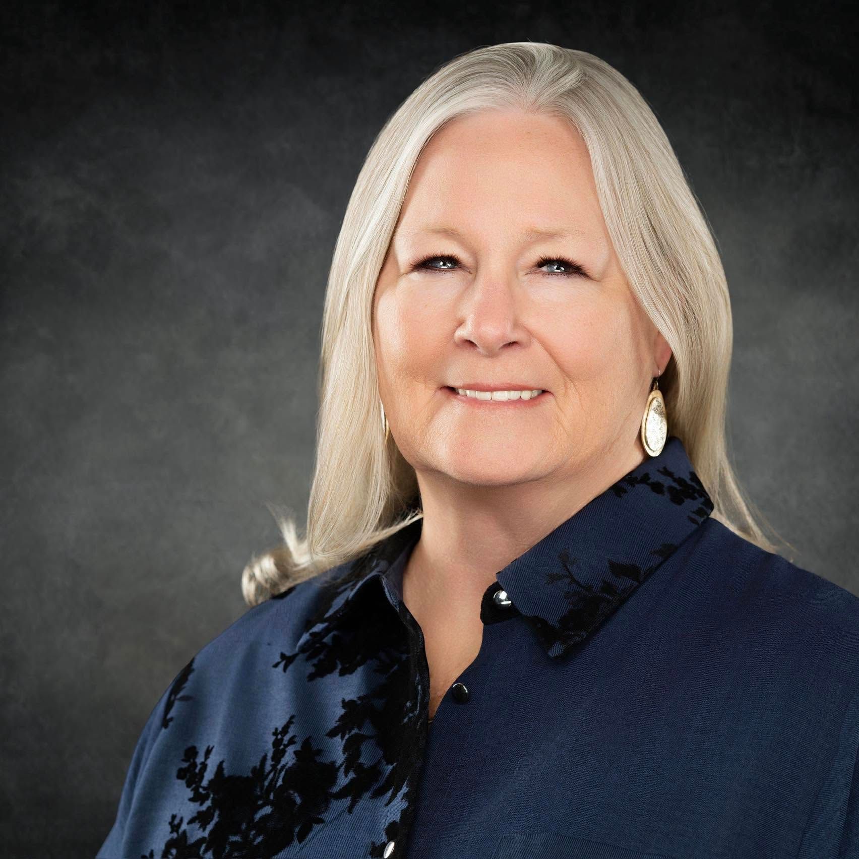 A man in a suit shakes hands with another man in a blue shirt