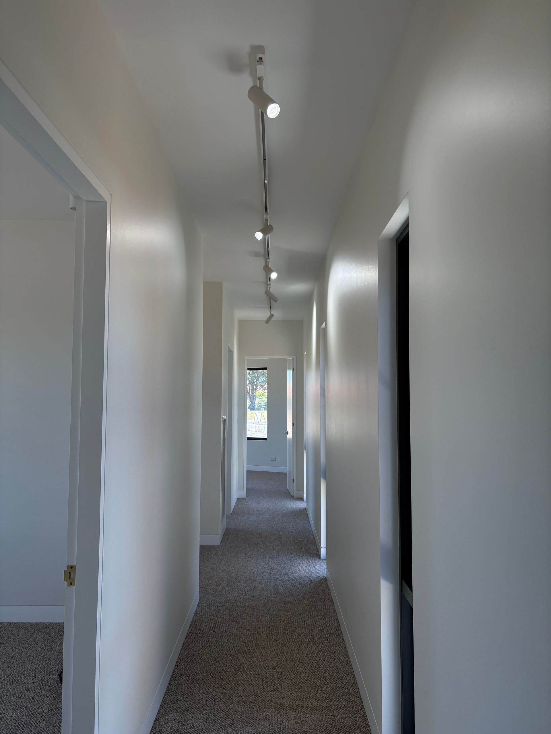 Narrow hallway with white walls, carpeted floor, and track lighting — SJD Electrical Contracting in Forbes, NSW