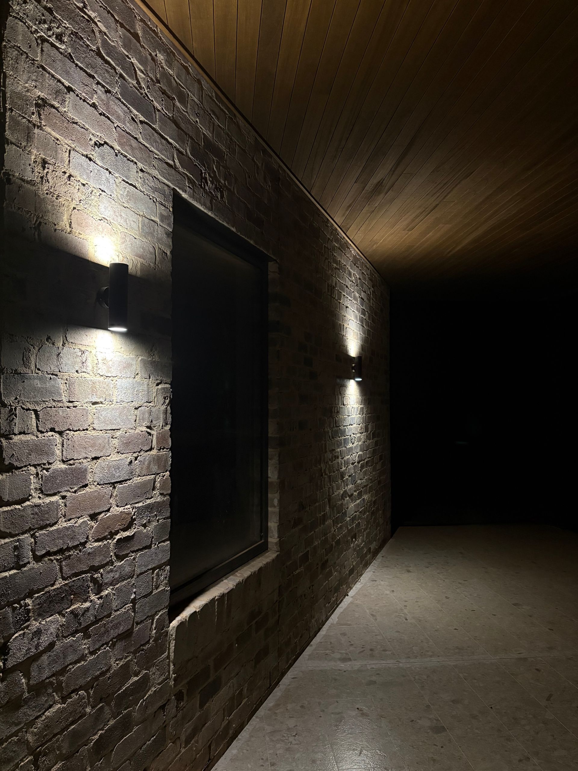 Brick wall with two sconce lights, window, and dark hallway — SJD Electrical Contracting in Cowra, NSW