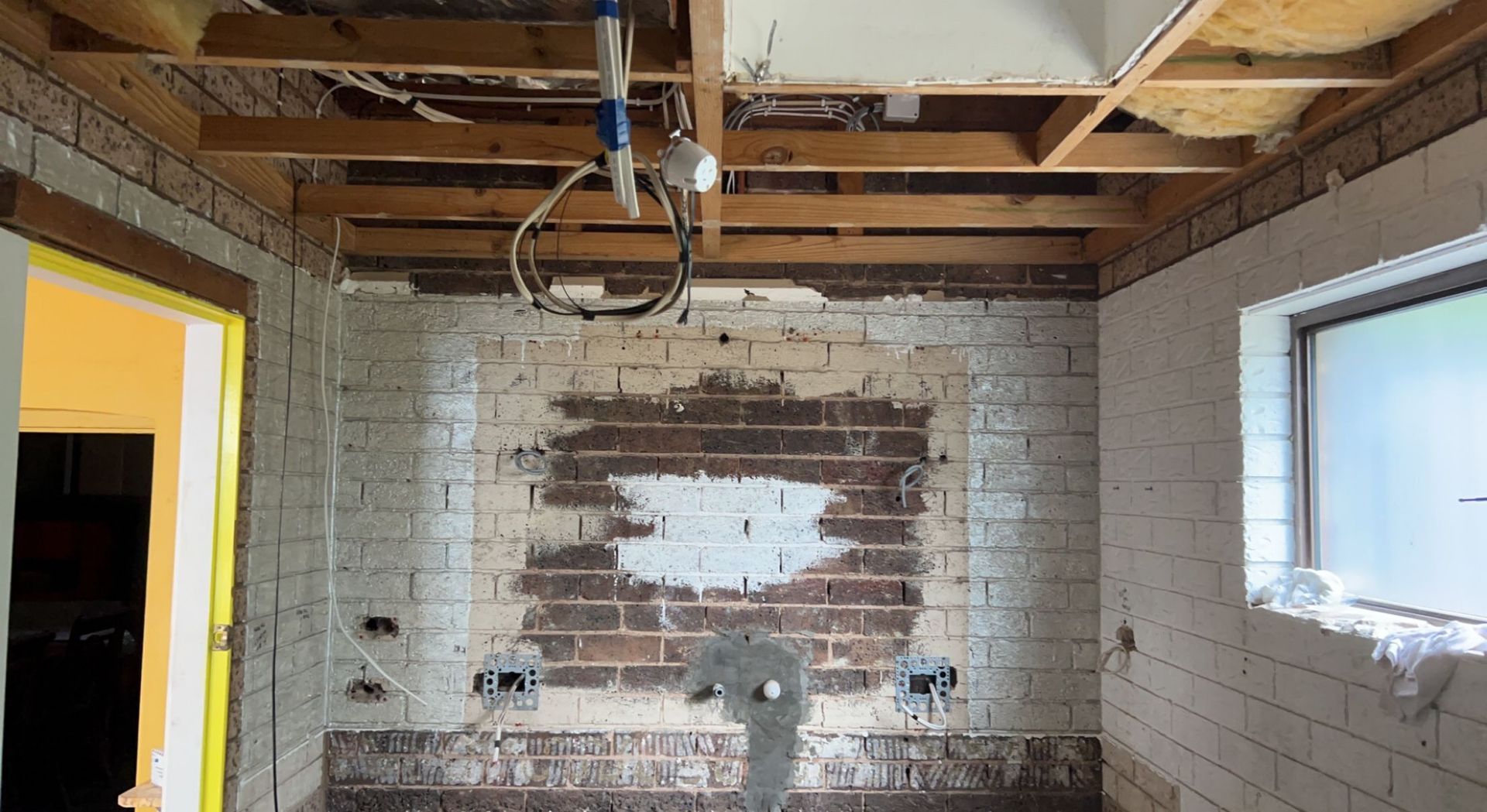 Bathroom remodel in progress; exposed brick wall, unfinished ceiling, window, and plumbing — SJD Electrical Contracting in Lithgow, NSW