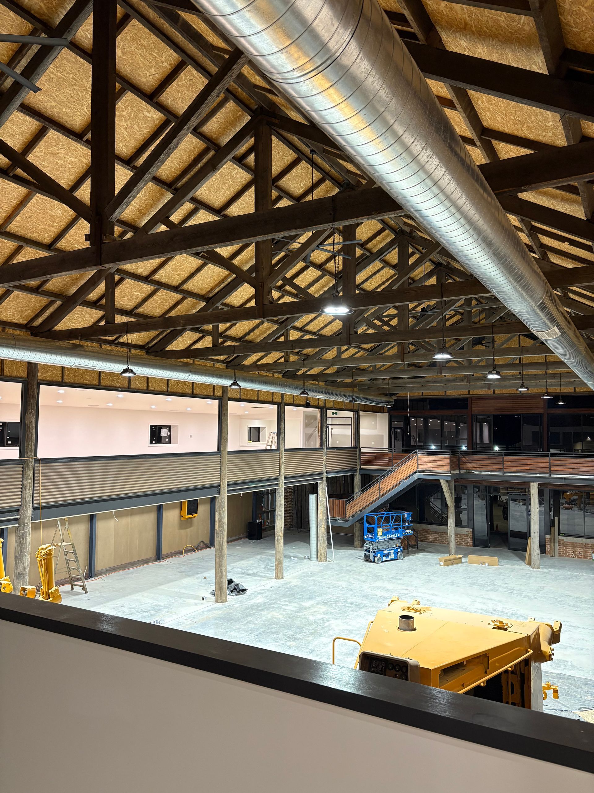 Large interior warehouse with exposed wooden beams, concrete floor, and heavy machinery — SJD Electrical Contracting in Forbes, NSW