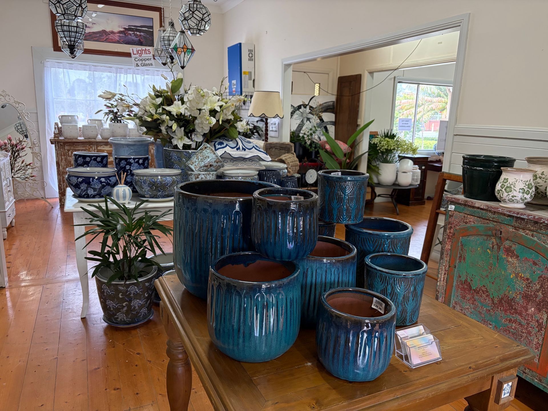 Blue ceramic planters displayed on a wooden table in a bright home decor shop — Hunter Valley Plant Market in Nulkaba, NSW